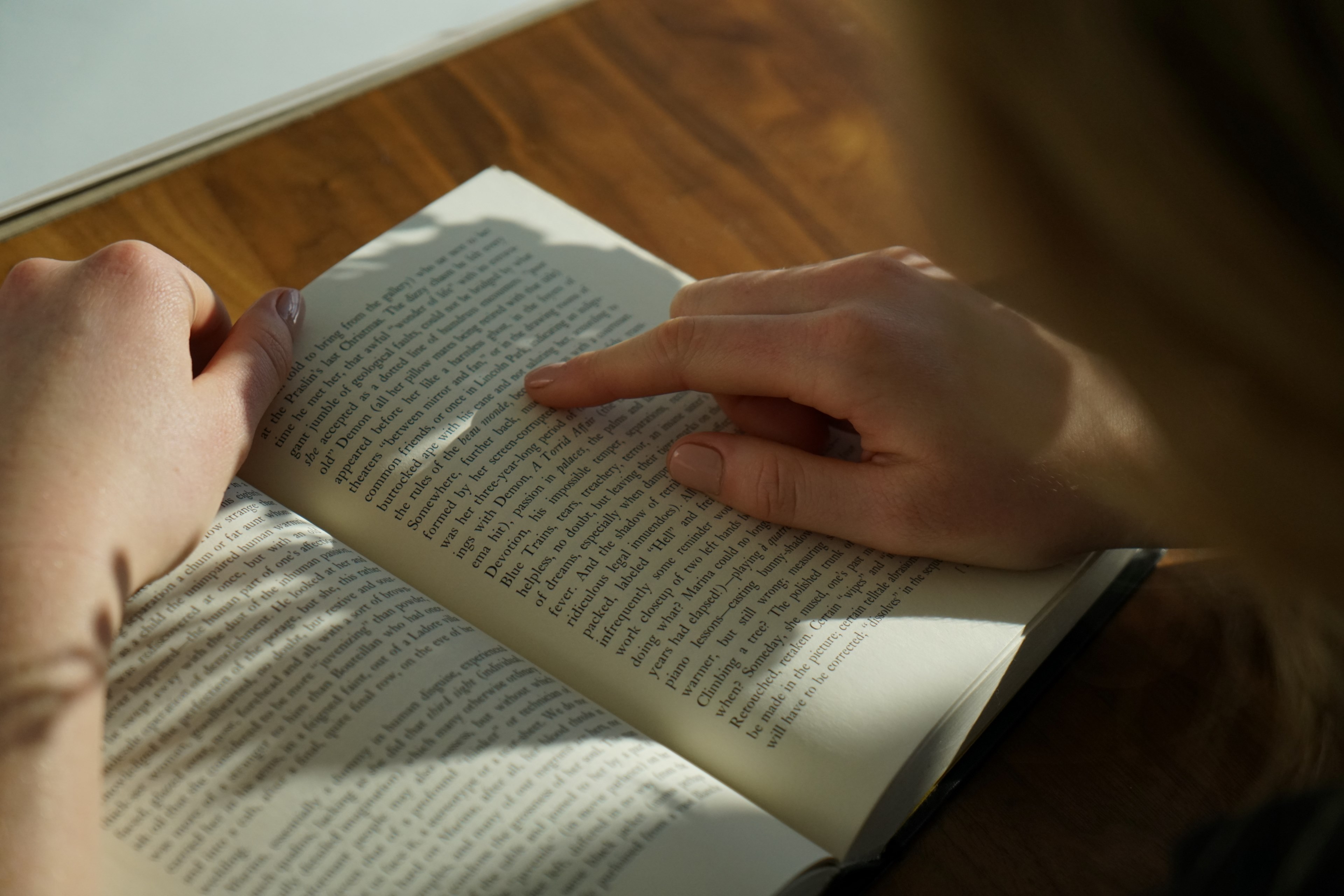 person reading a book uses their finger to keep their page, woman reads a book on a wooden desk 4k, HD Wallpaper