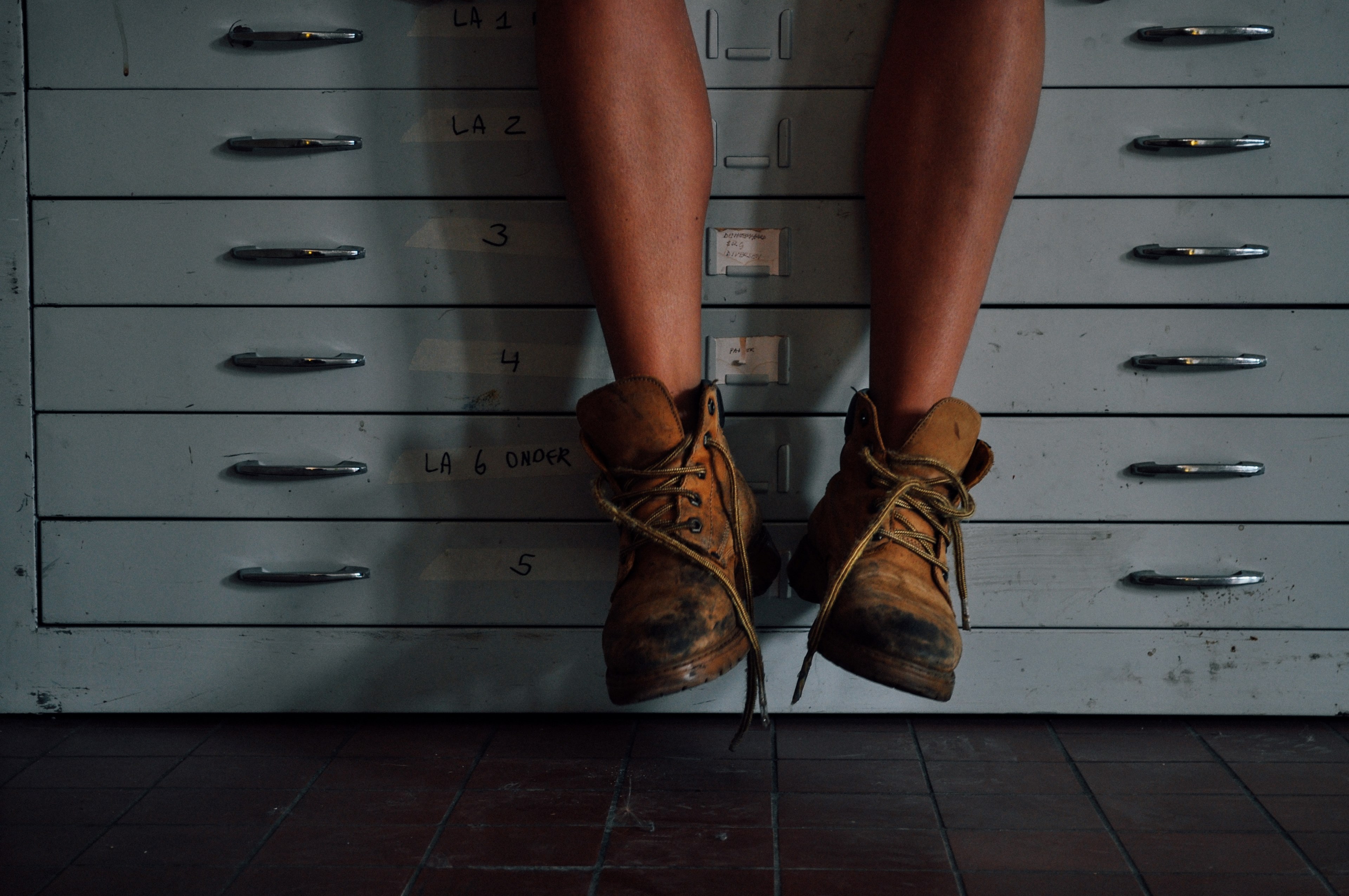 a person sitting on a countertop with drawers wearing worn out work boots in deventer, deventer work boots 4k, HD Wallpaper