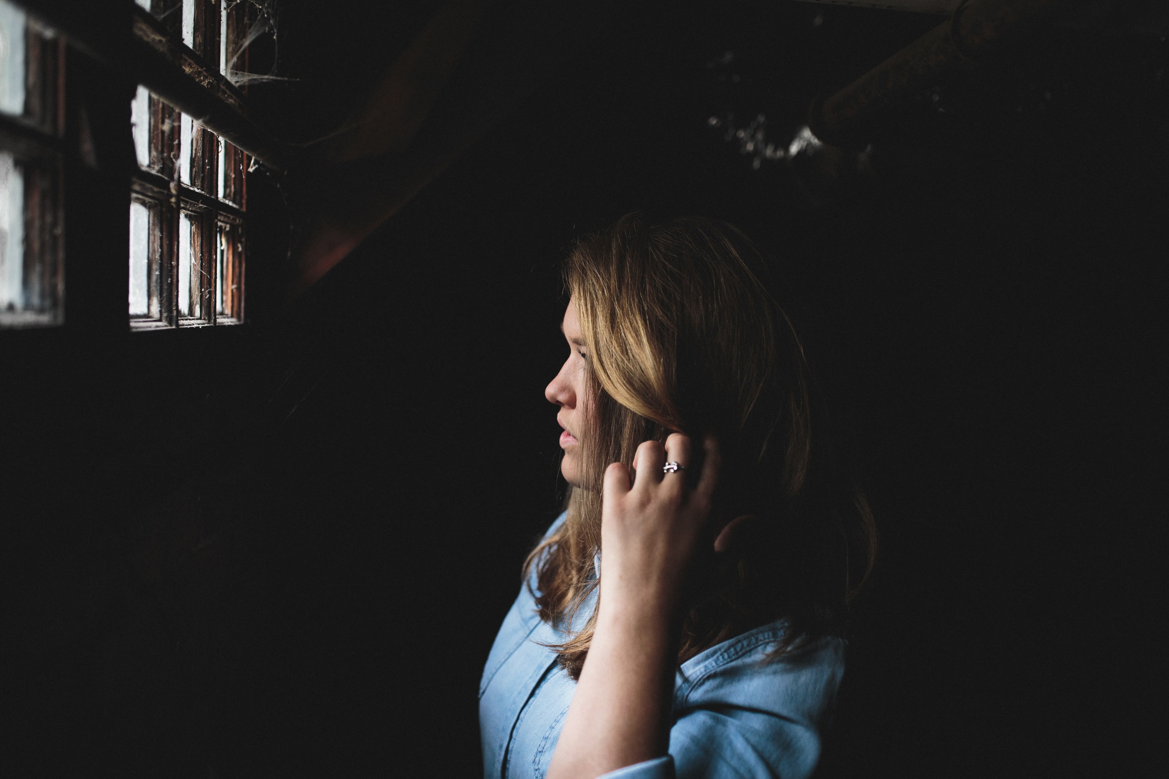 woman with blonde hair wearing a blue shirt and ring looking out of a window covered in spider webs, woman looking out window 4k, HD Wallpaper