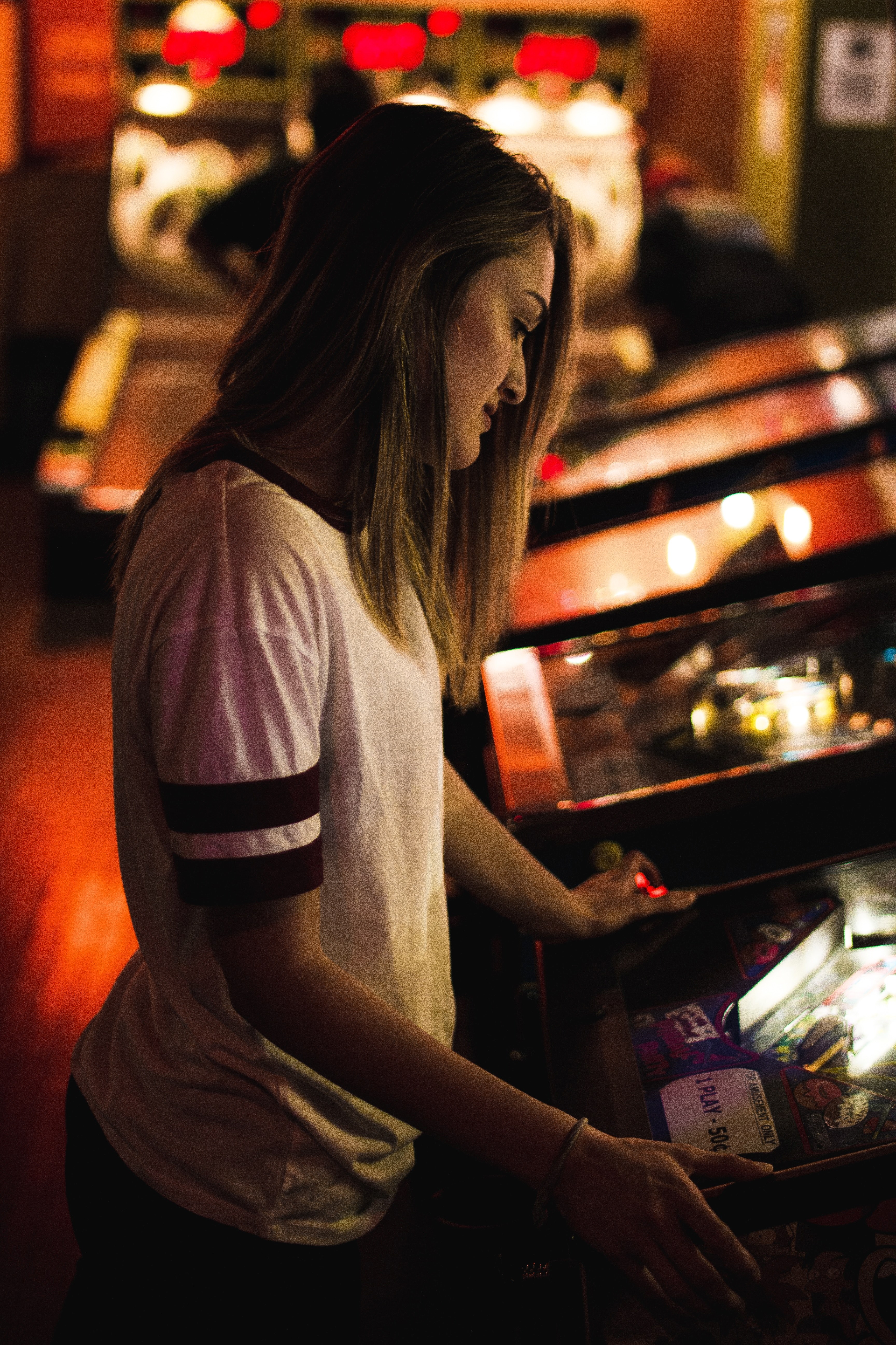 a woman with medium length brown hair plays a game in an arcade, woman playing arcade game 4k, Phone HD Wallpaper
