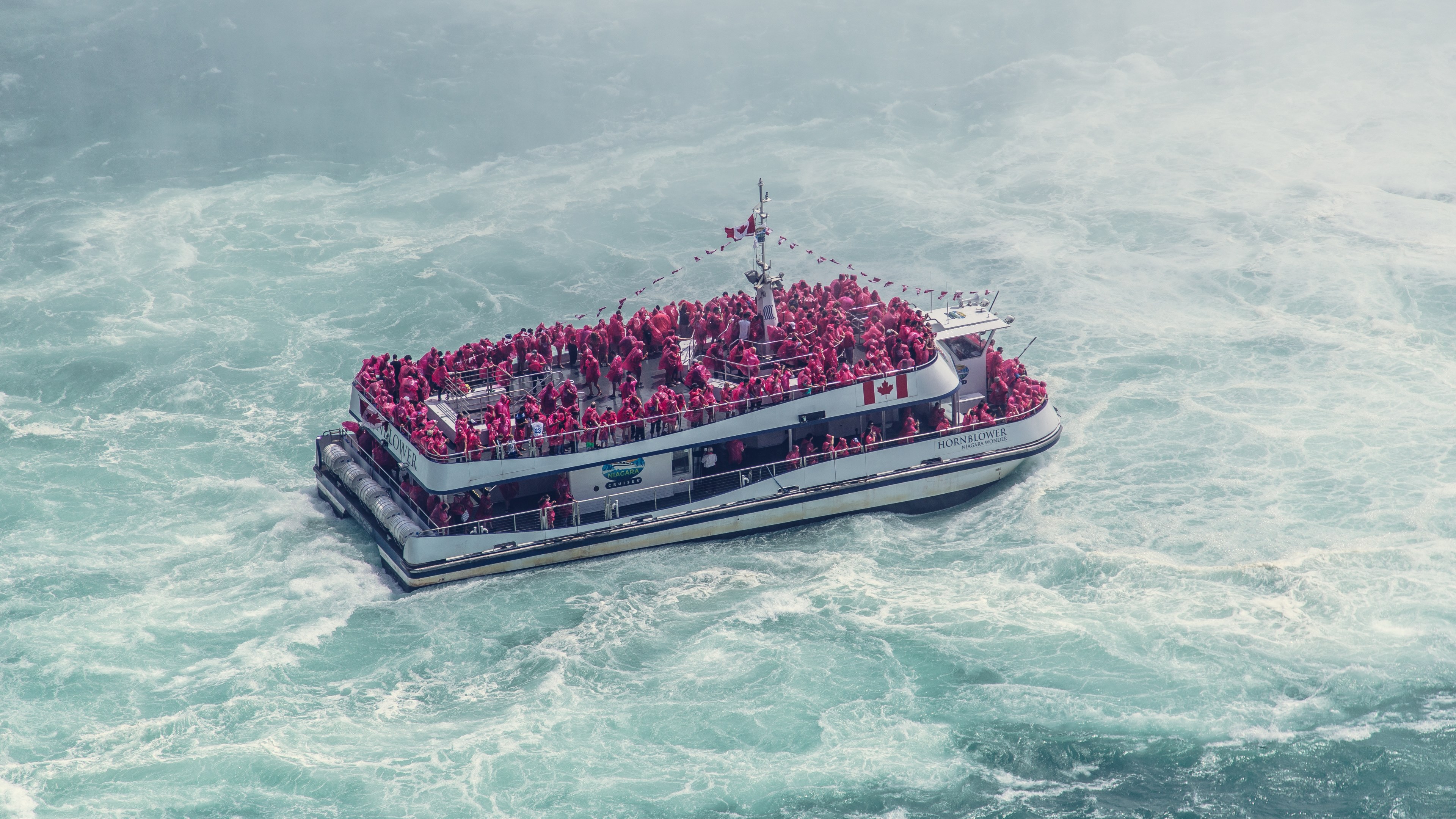 a boat full of tourists in red life jackets on the frothy water near niagara falls, sightseeing on a boat 4k, HD Wallpaper