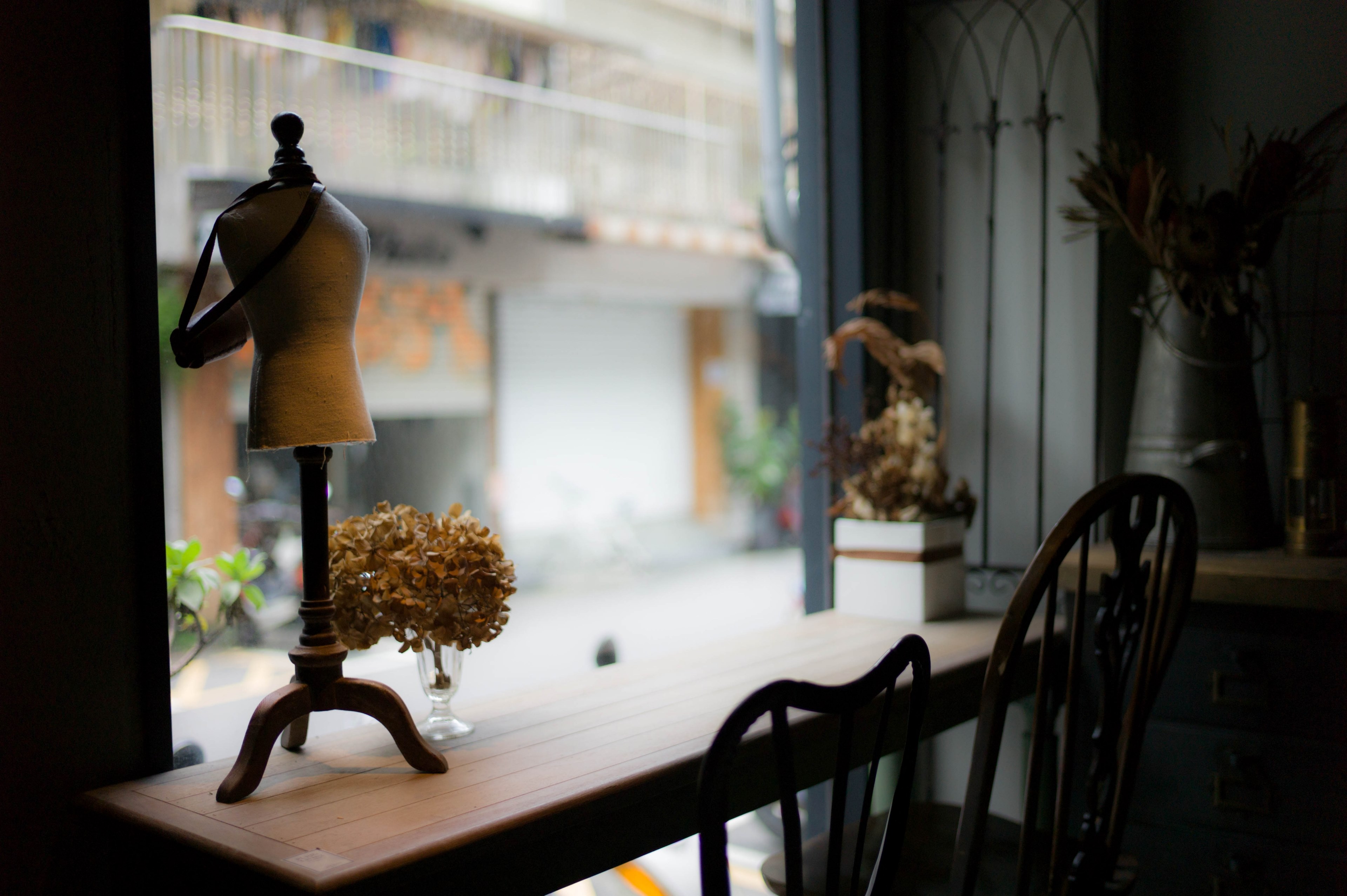 a narrow table with dried flowers on it near a store window, narrow caf table 4k, HD Wallpaper