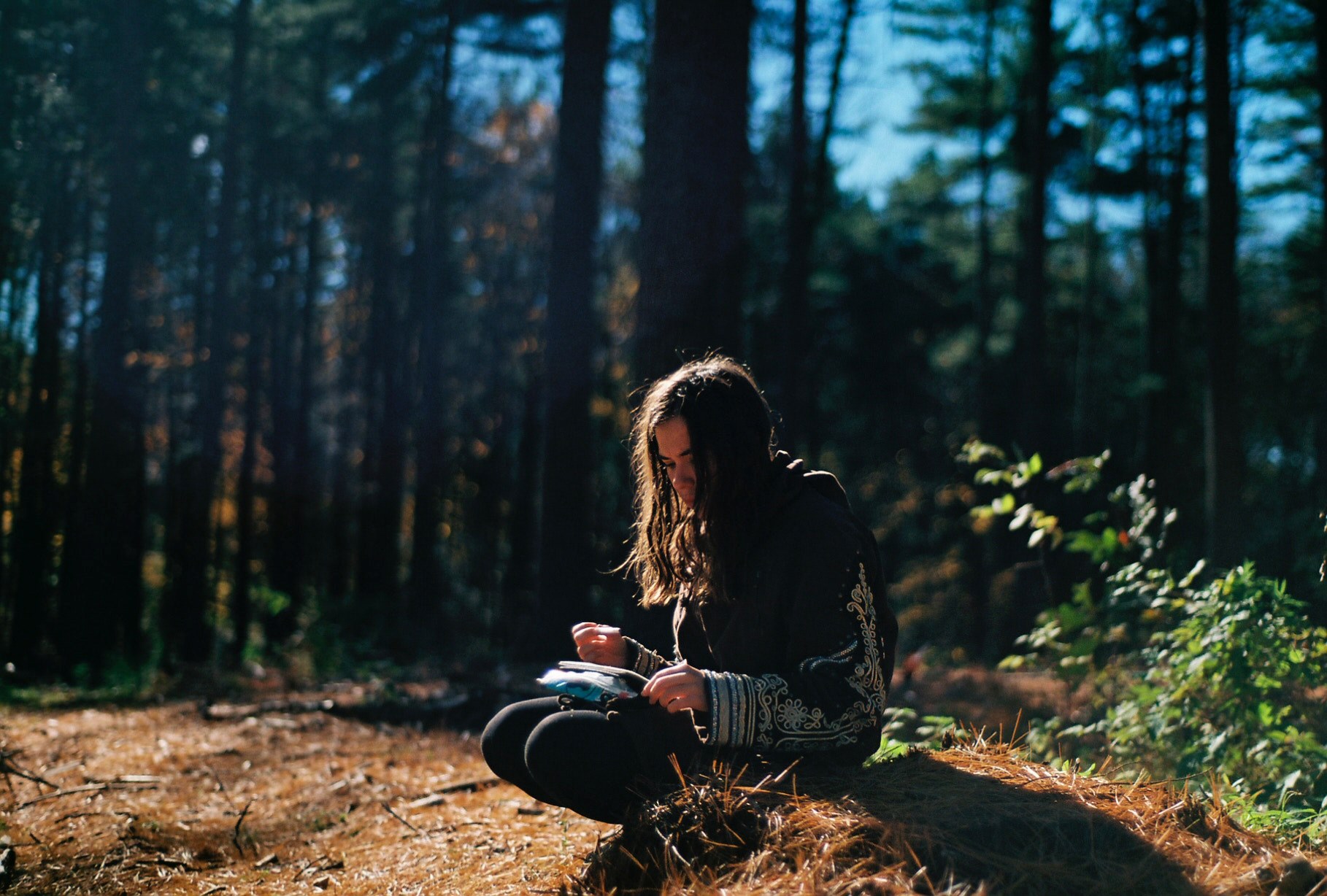 a pensive dark haired girl crouching on the forest floor journaling, scribbling in the forest 4k, HD Wallpaper