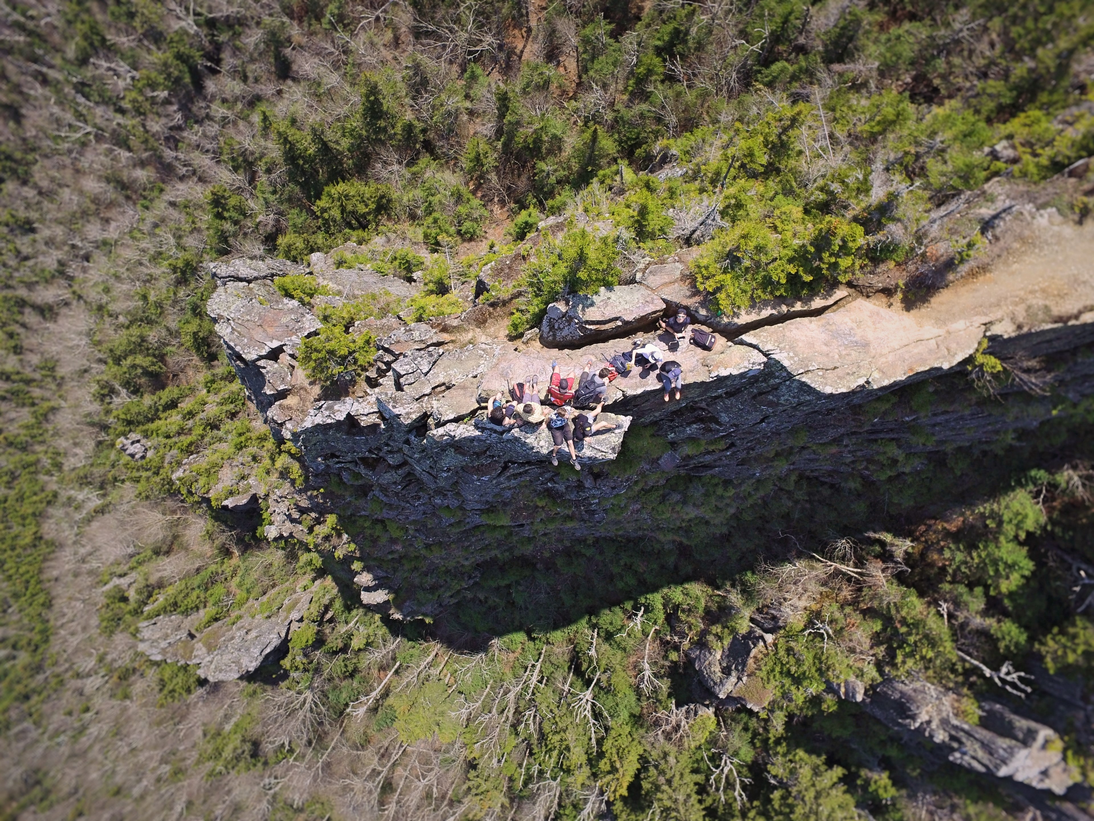 a drone shot of a group of people resting on a rocky ledge in a forest, resting hikers from above 4k, HD Wallpaper