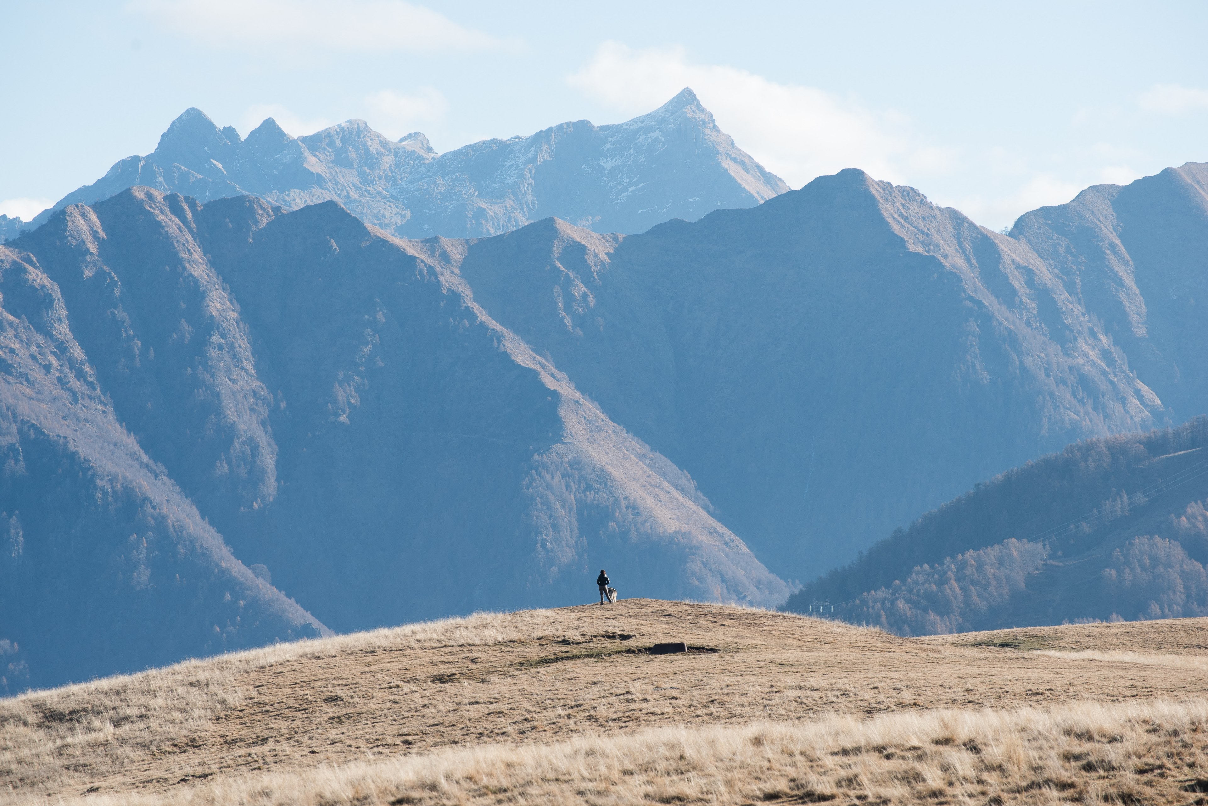 a silhouette of a person standing at the edge of a slight slope and looking off into the tall mountains, hiker in the tall mountains 4k, HD Wallpaper