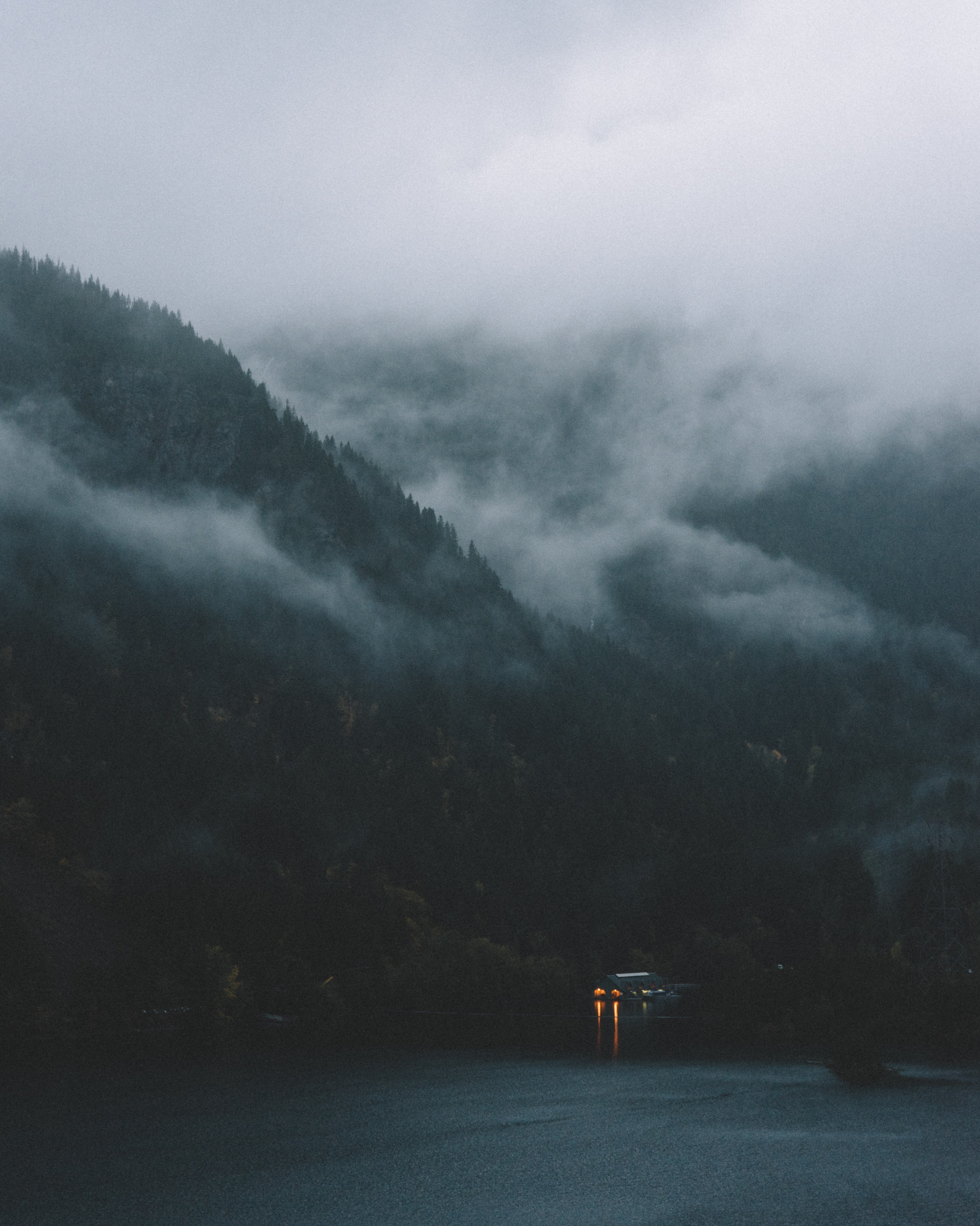 a dim shot of a cottage on the shore of a mountain lake with a thick fog on the slopes, quiet before the storm 4k, Phone HD Wallpaper