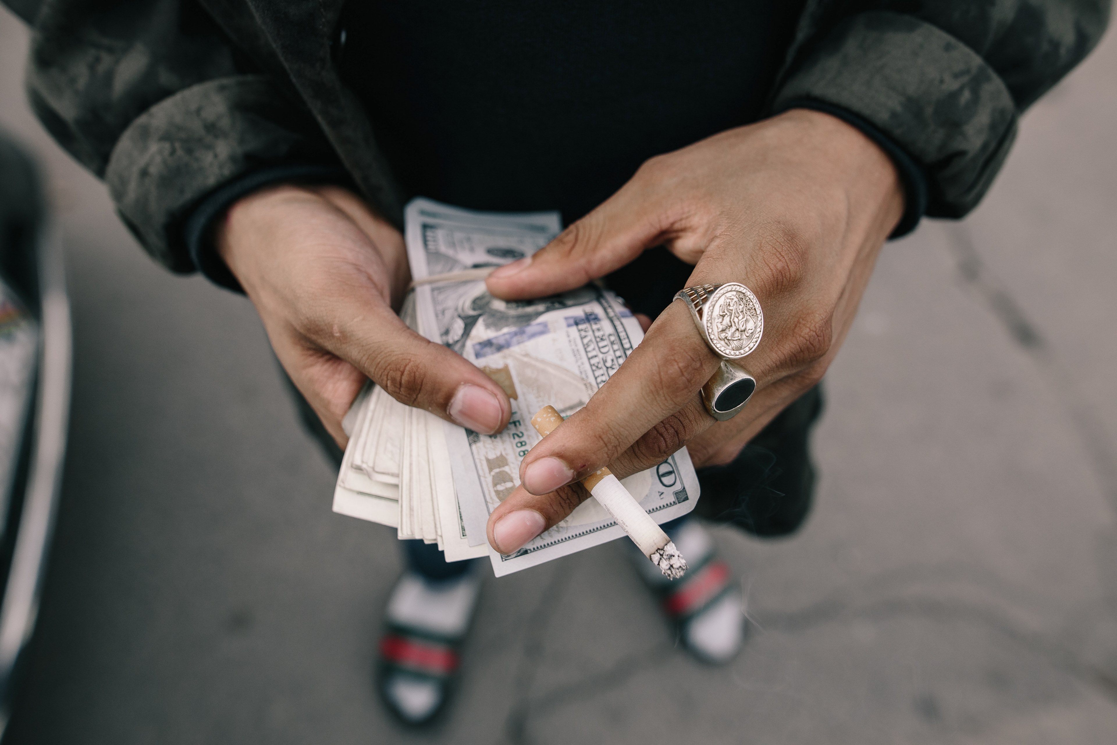 close up of a mans hands holding a bundle of dollar bills and a cigarette, doing business in the street 4k, HD Wallpaper