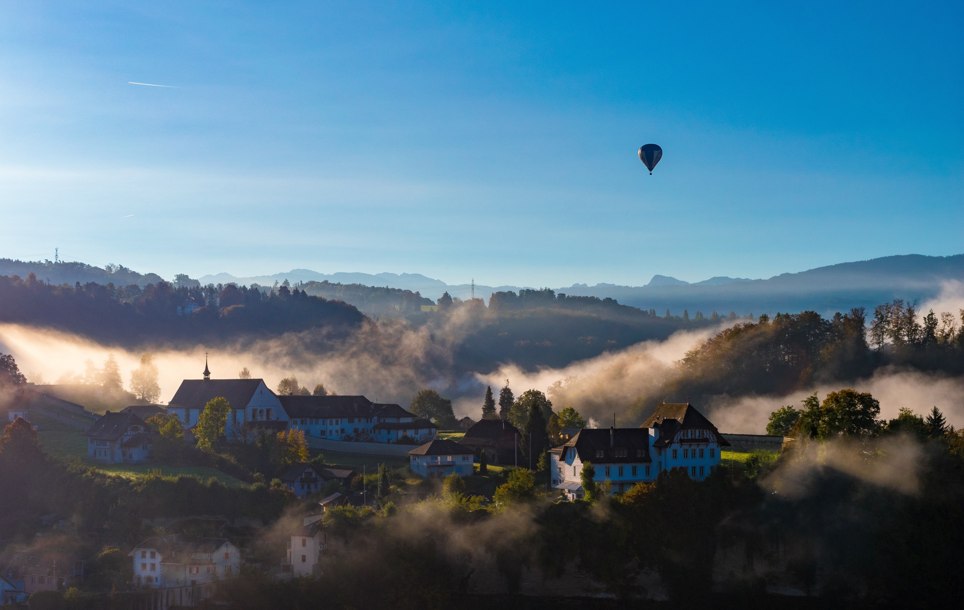 hot air balloon flies over a quaint village in fribourg on a foggy day, just a little walk on sunday morning 4k, HD Wallpaper