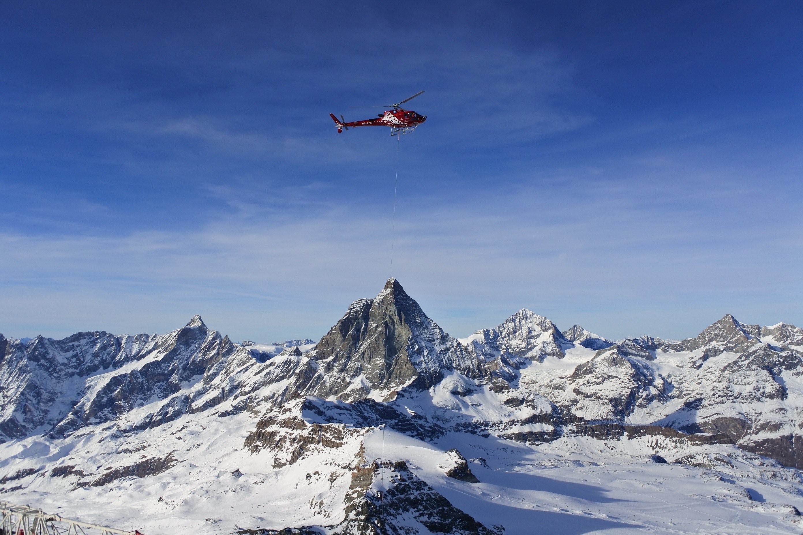 a rescue helicopter with a rescue hoist in the air above snowy mountains, beautiful december day in a swiss resort zermatt 4k, HD Wallpaper