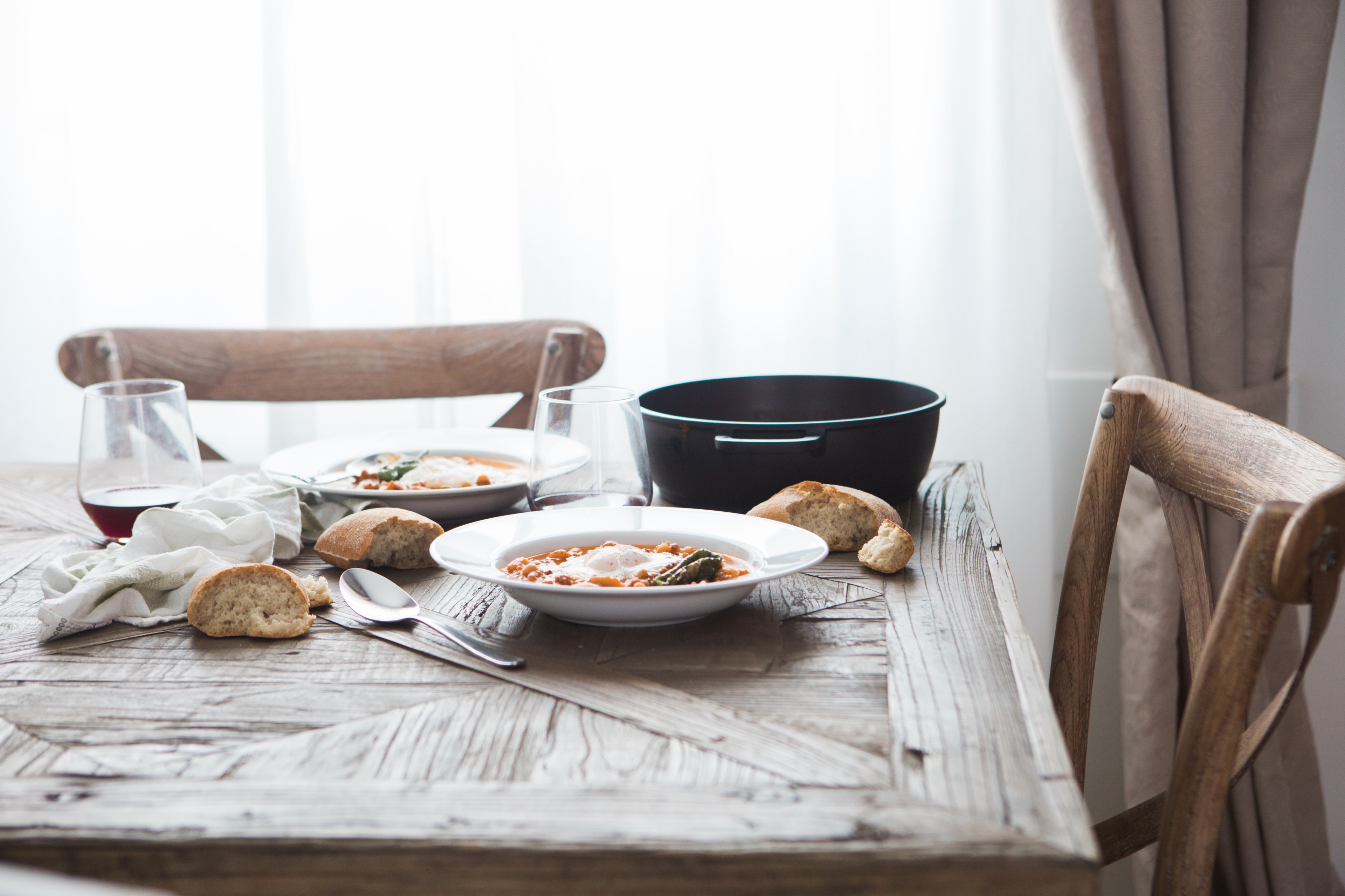 two deep dishes with a hearty meal pieces of bread and wine glasses on a wooden table, classy meal for two 4k, HD Wallpaper