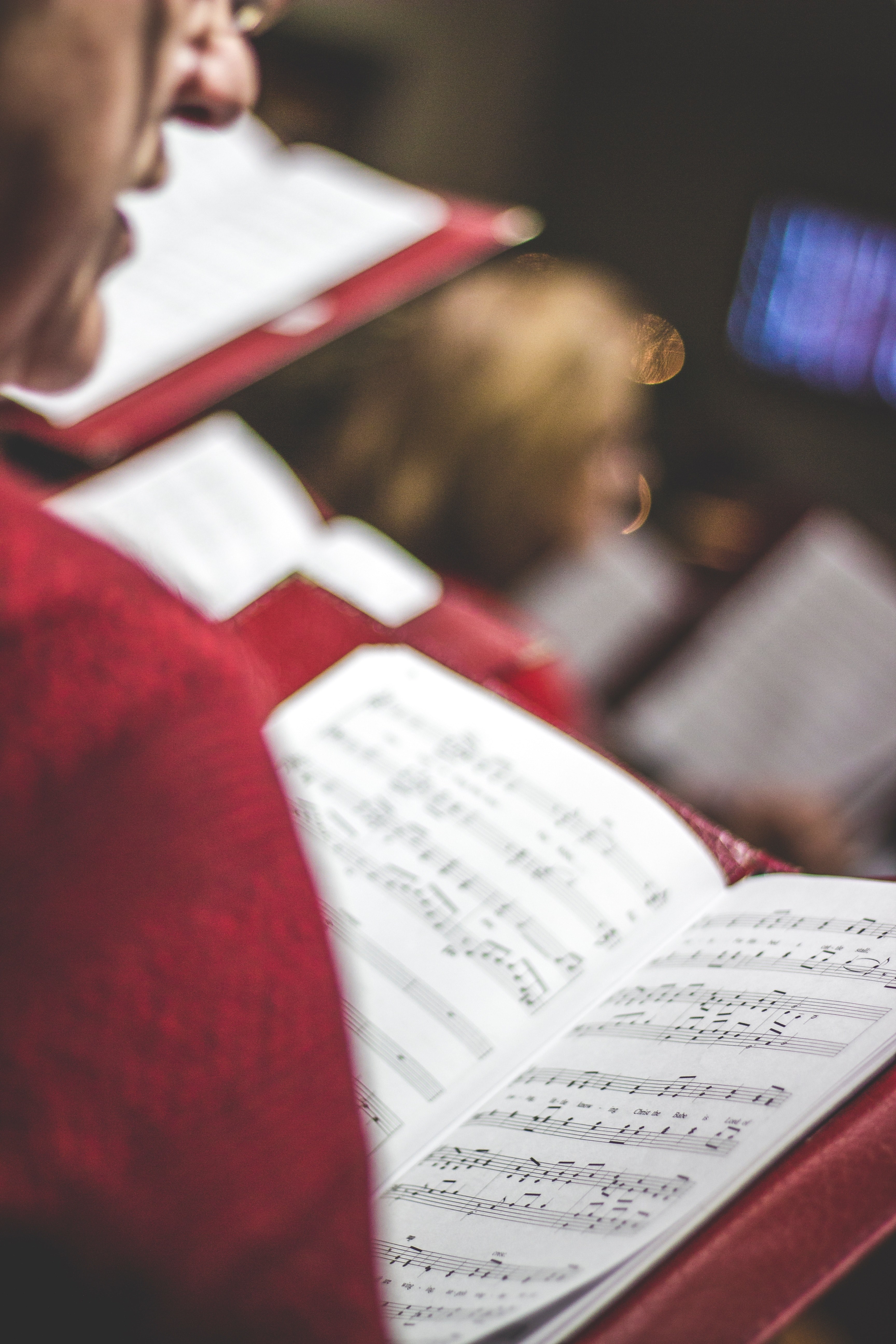 a member of a chorus singing while looking down a music score in a red leather case, chorus member singing 4k, Phone HD Wallpaper