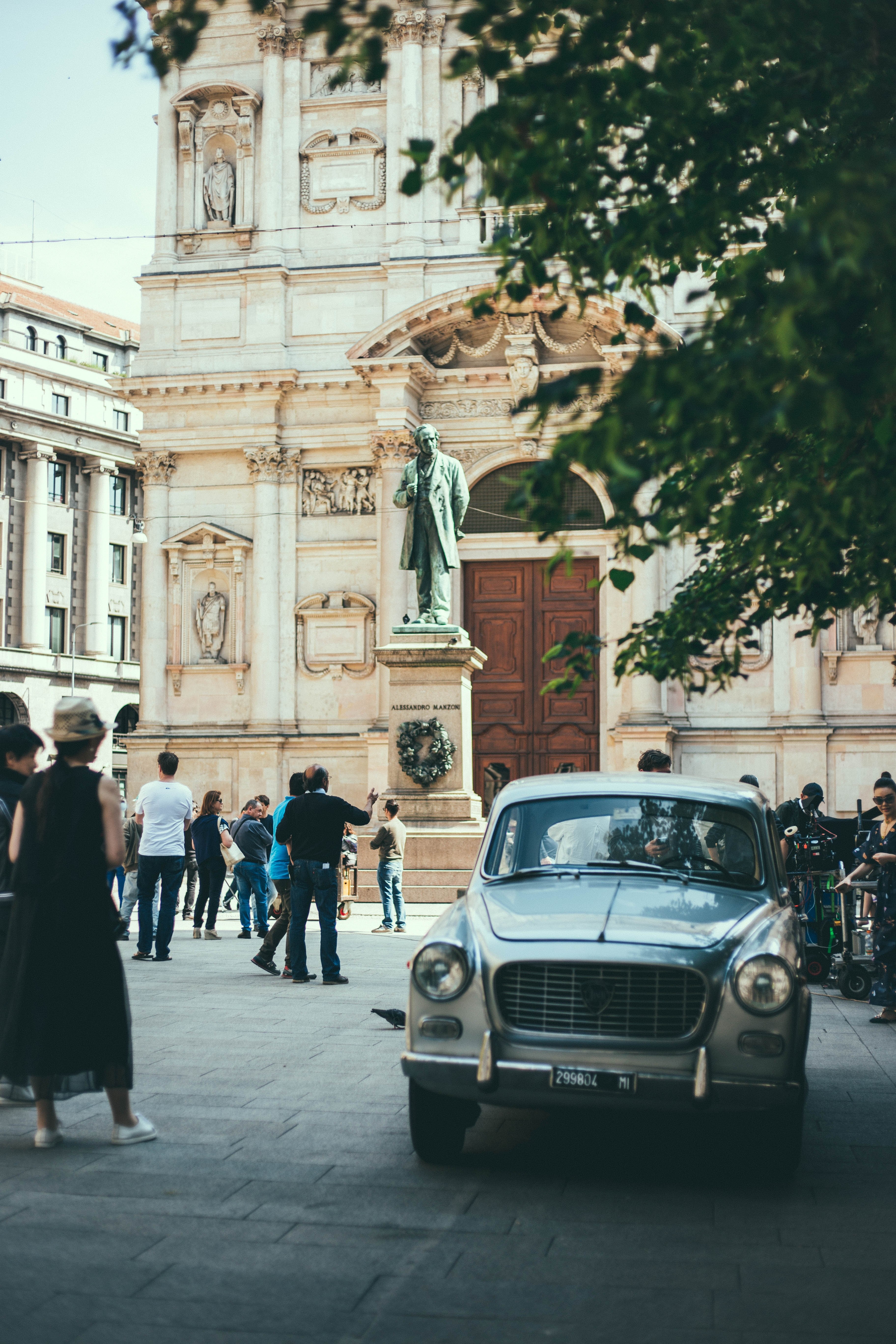old vintage white car parked on the crowded square in front of the statue and an old building in milan, vintage car parked on the square in milan 4k, Phone HD Wallpaper