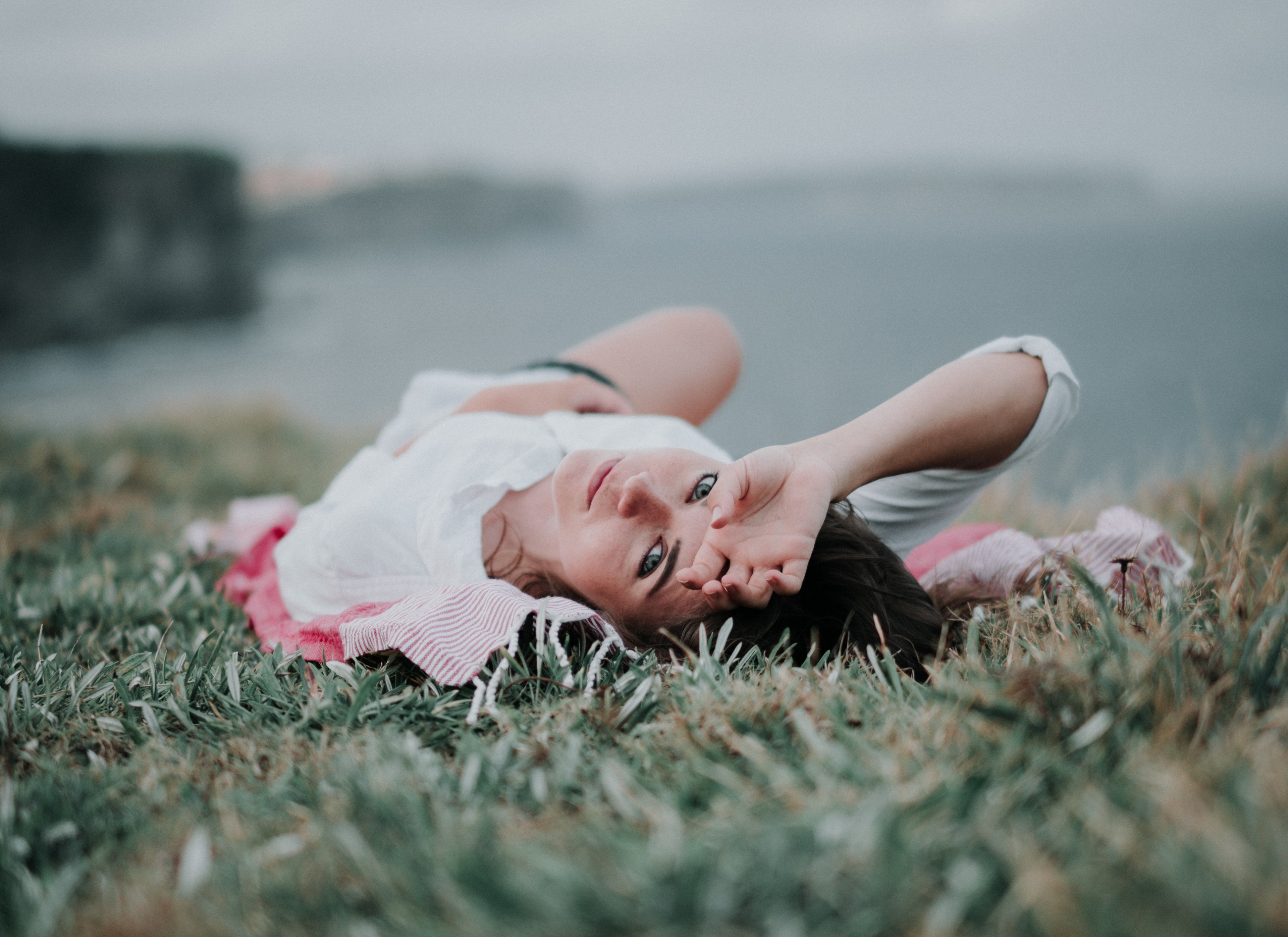 woman lying in the grass looking at the camera at bondi beach, cliffs at sunset 4k, HD Wallpaper