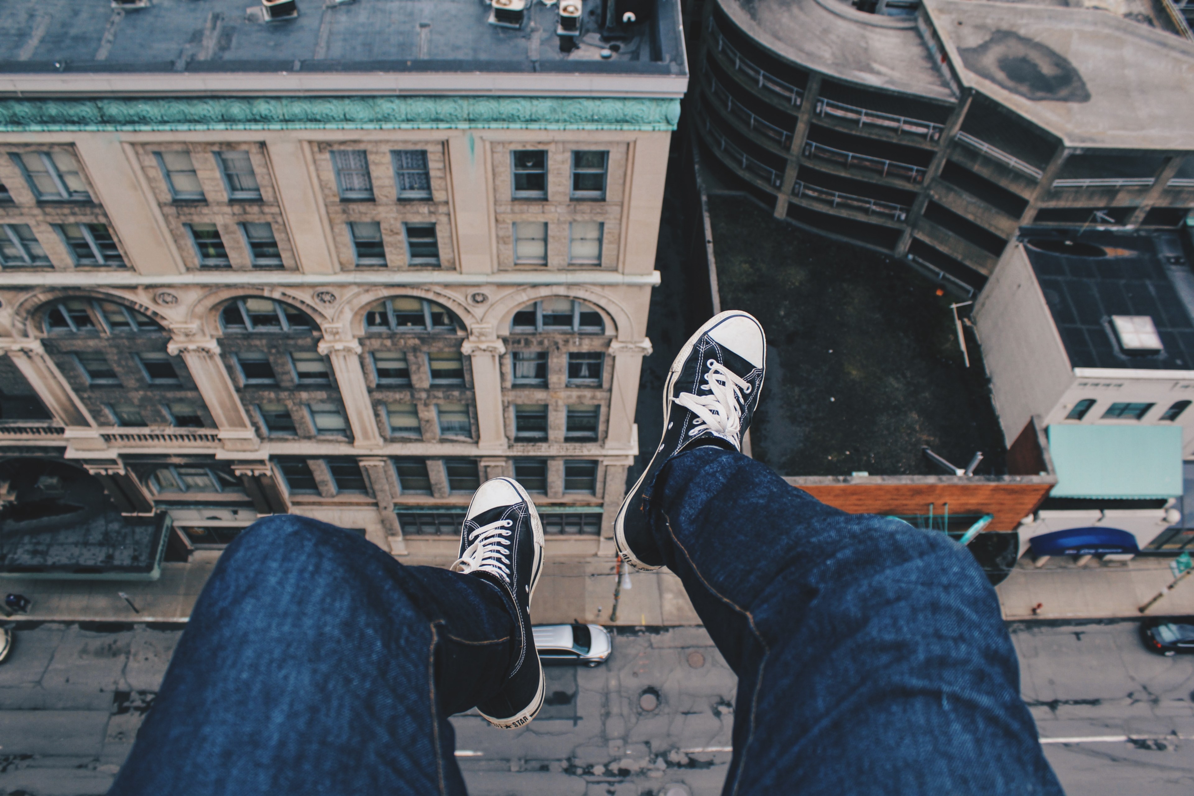 person wearing converse sneakers dangling their feet off buildings rooftop ledge above the traffic, feet dangling from a building 4k, HD Wallpaper