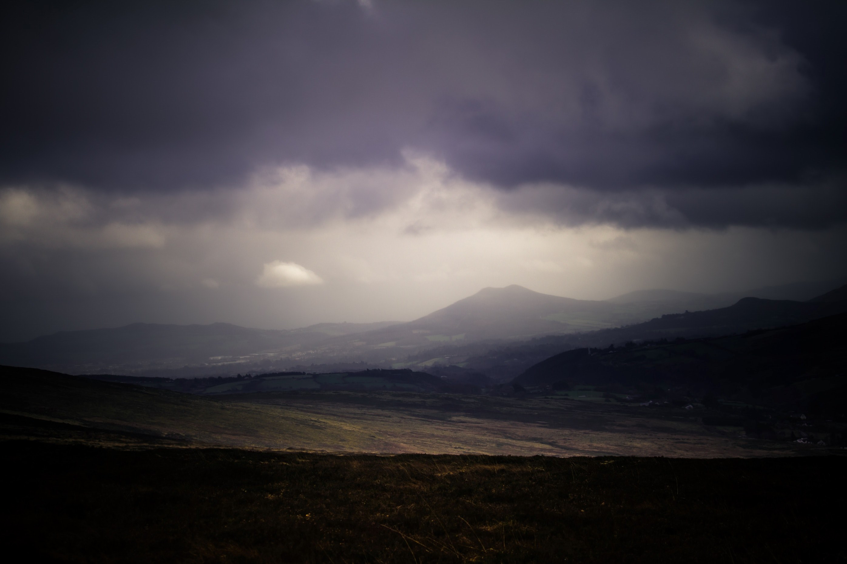 a dim shot of plains stretching to the low mountains on the horizon under gray clouds, dark plains in the mountains 4k, HD Wallpaper