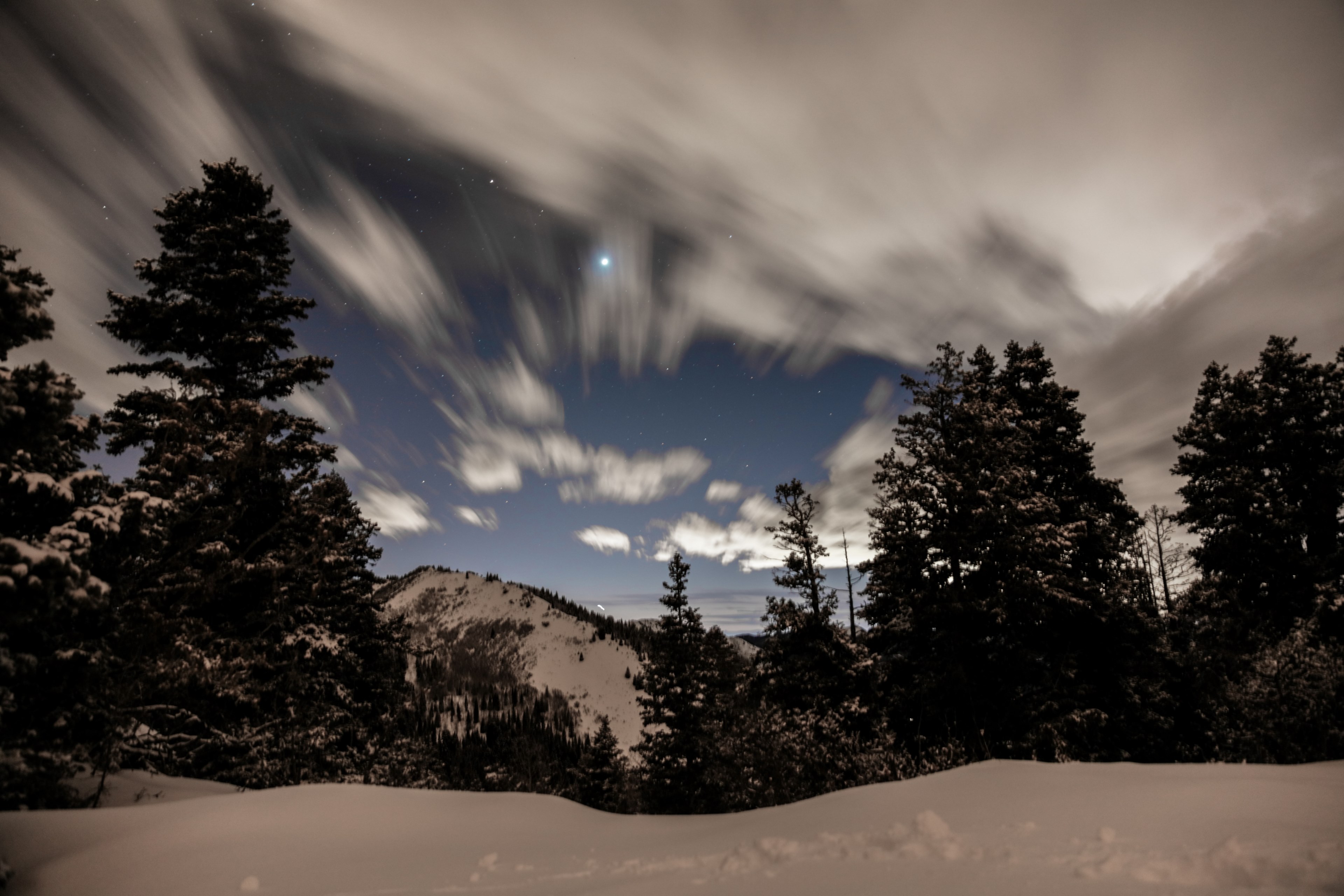 a long exposure shot of clouds moving slowly over a stretch of snow covered trees, moving clouds in the winter 4k, HD Wallpaper
