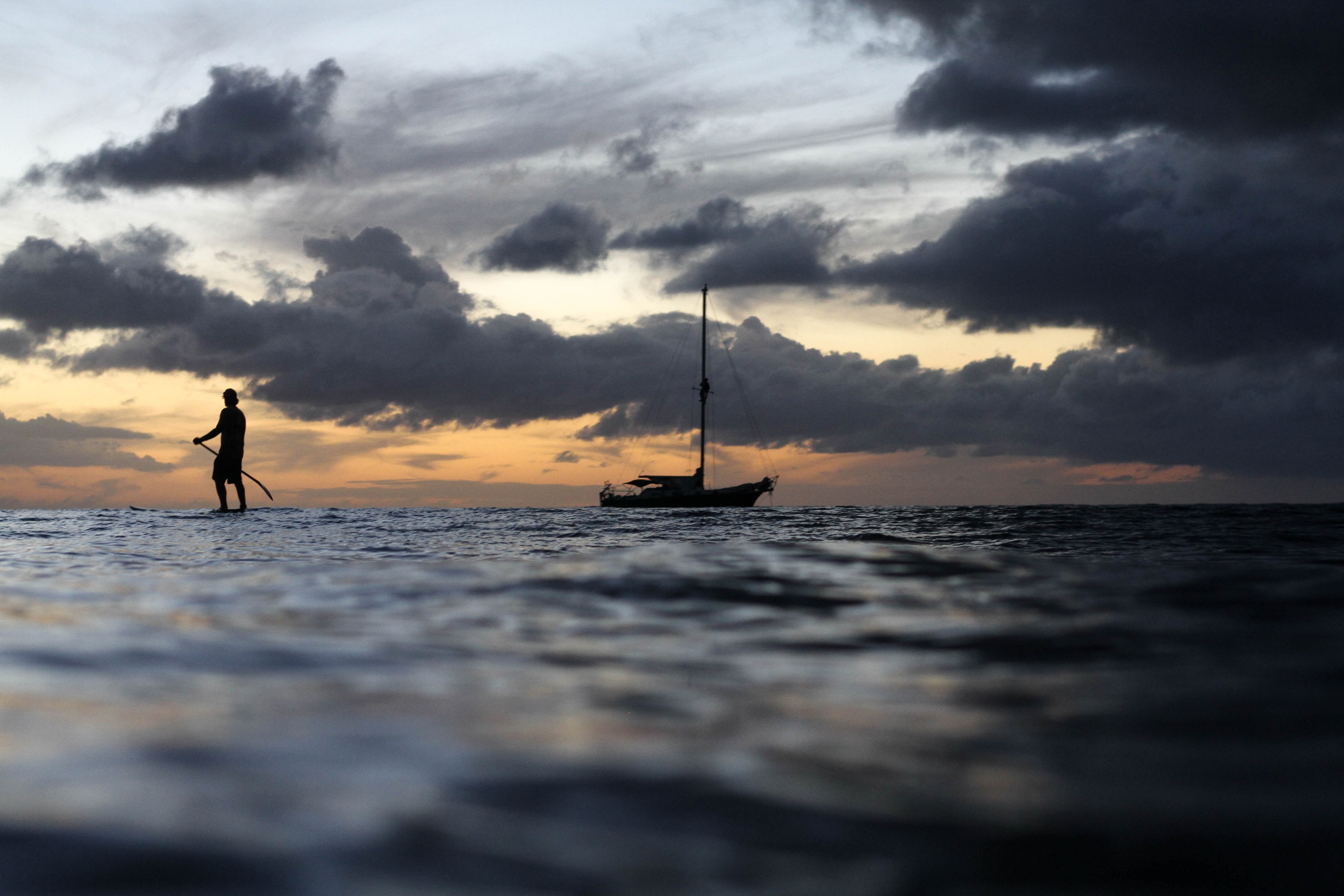 a person paddleboarding in the ocean at dawn with a sailboat in the distance, early morning exercise 4k, HD Wallpaper