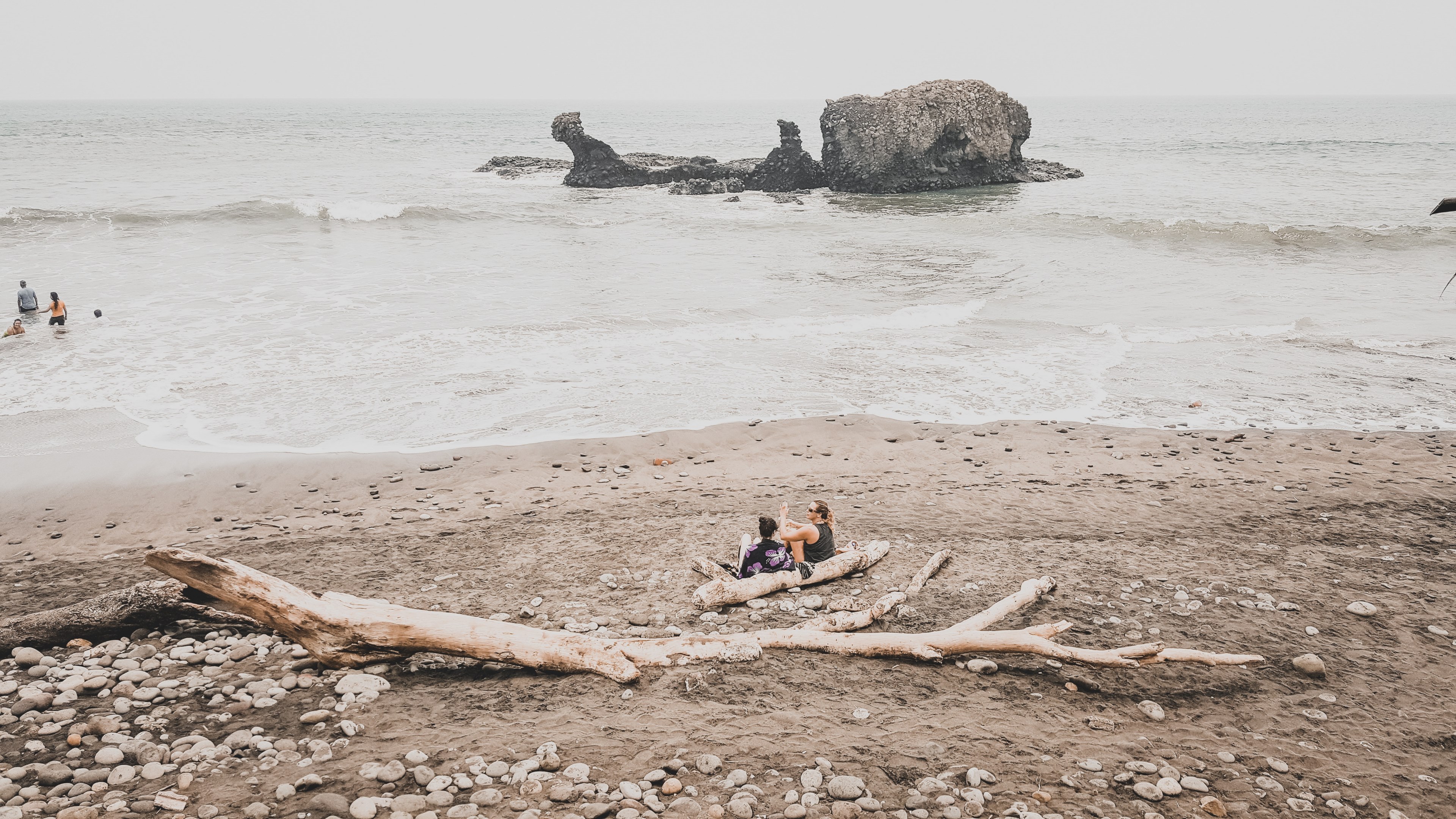 people hanging out on a beach sitting on driftwood and swimming in the ocean, driftwood beach 4k, HD Wallpaper