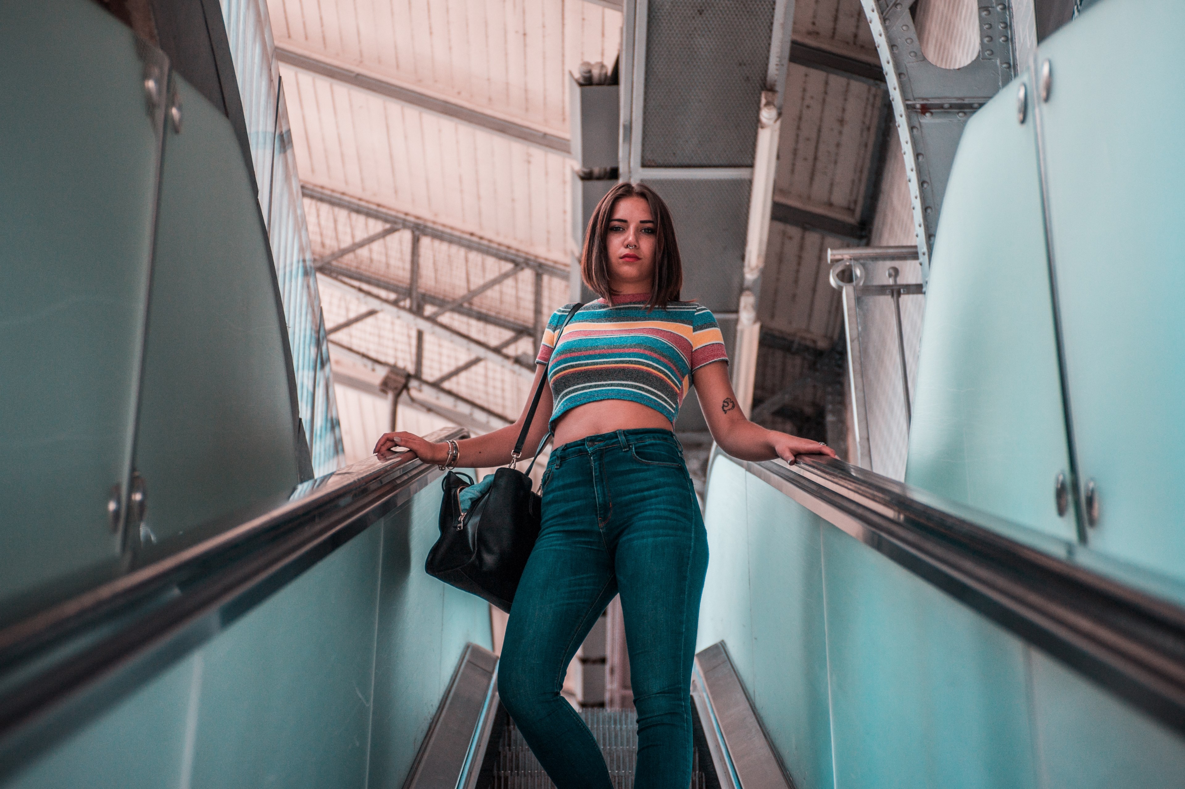 a girl wearing a striped shirt and denim jeans standing on an escalator, woman descending escalator 4k, HD Wallpaper