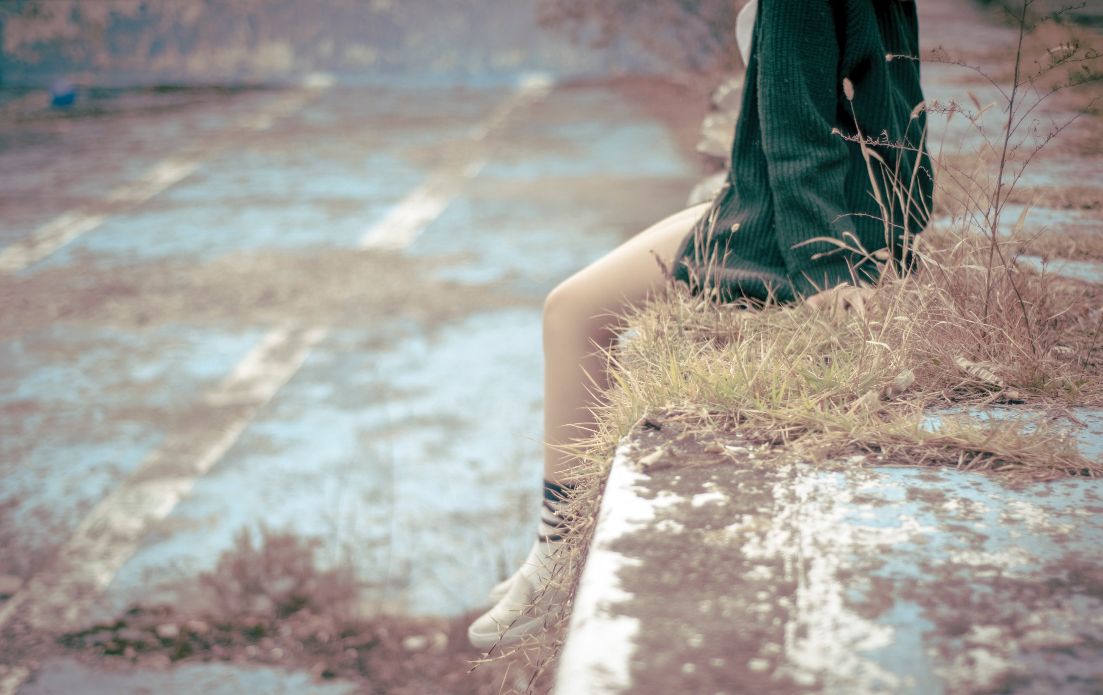 a person with bare legs and a green sweater sits on a dirty grassy wall, person on dirty wall 4k, HD Wallpaper