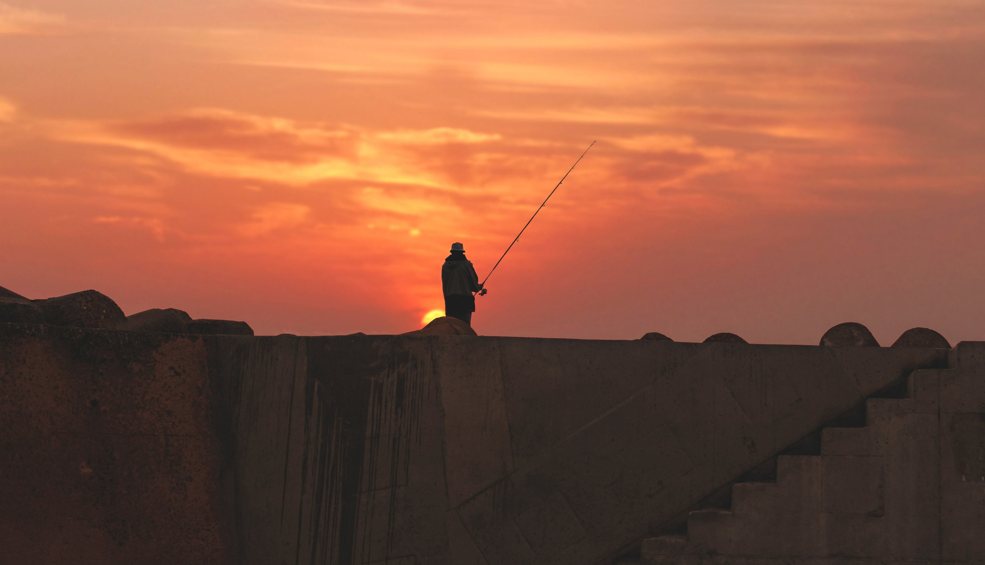 a silhouette of a fisherman standing atop a wall in asilah morocco during sunset, fishing in asilah at sunset 4k, HD Wallpaper