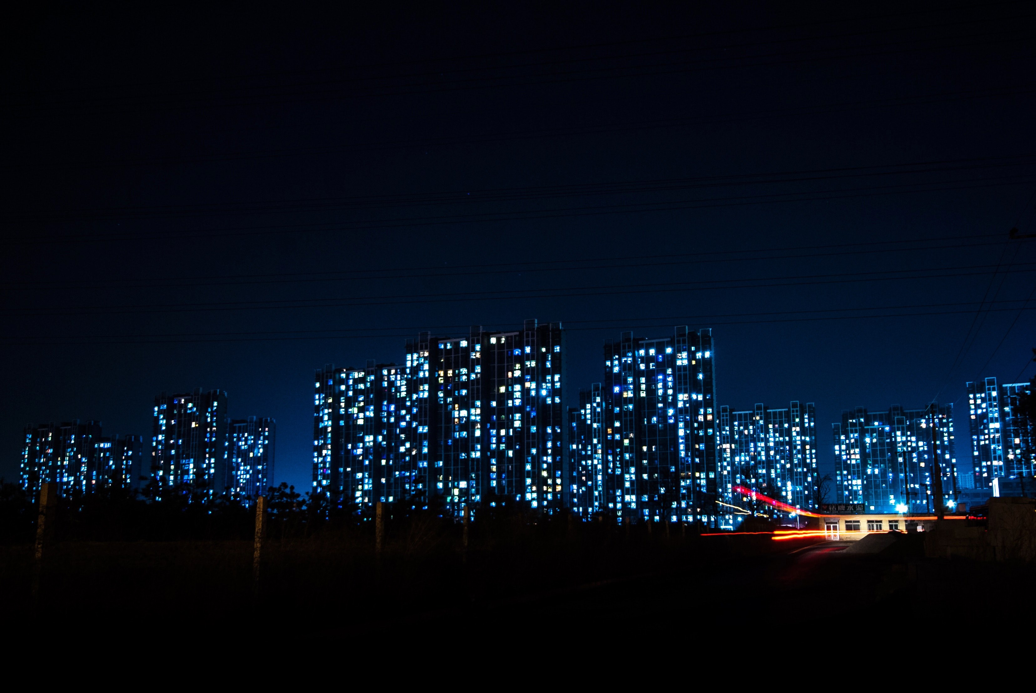 an illuminated city with more than half a dozen large buildings and skyscrapers with blue lights in the background, home lights 4k, HD Wallpaper