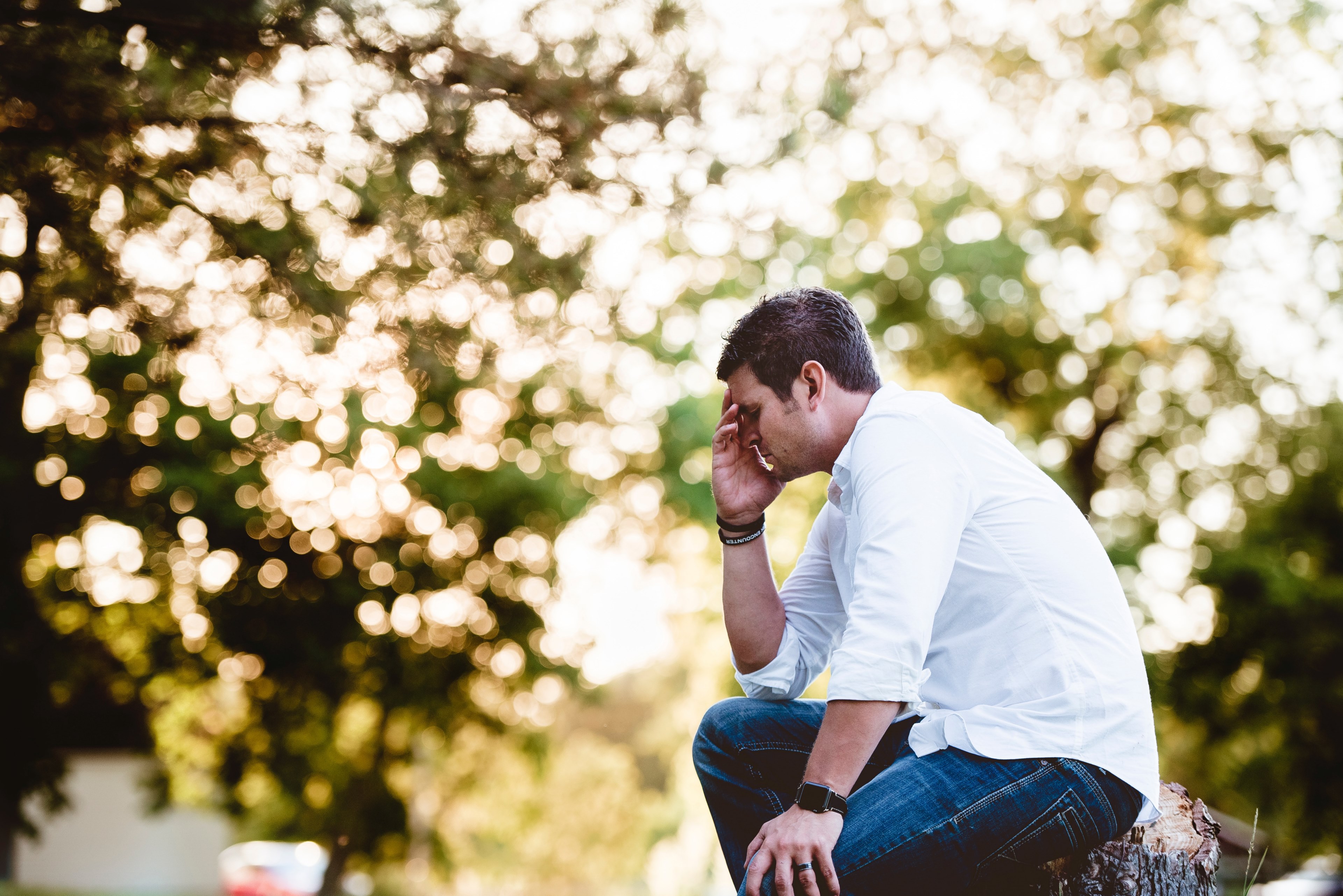 a man wearing a white button up shirt and jeans sitting on a tree stump thinking, sad man thinking 4k, HD Wallpaper