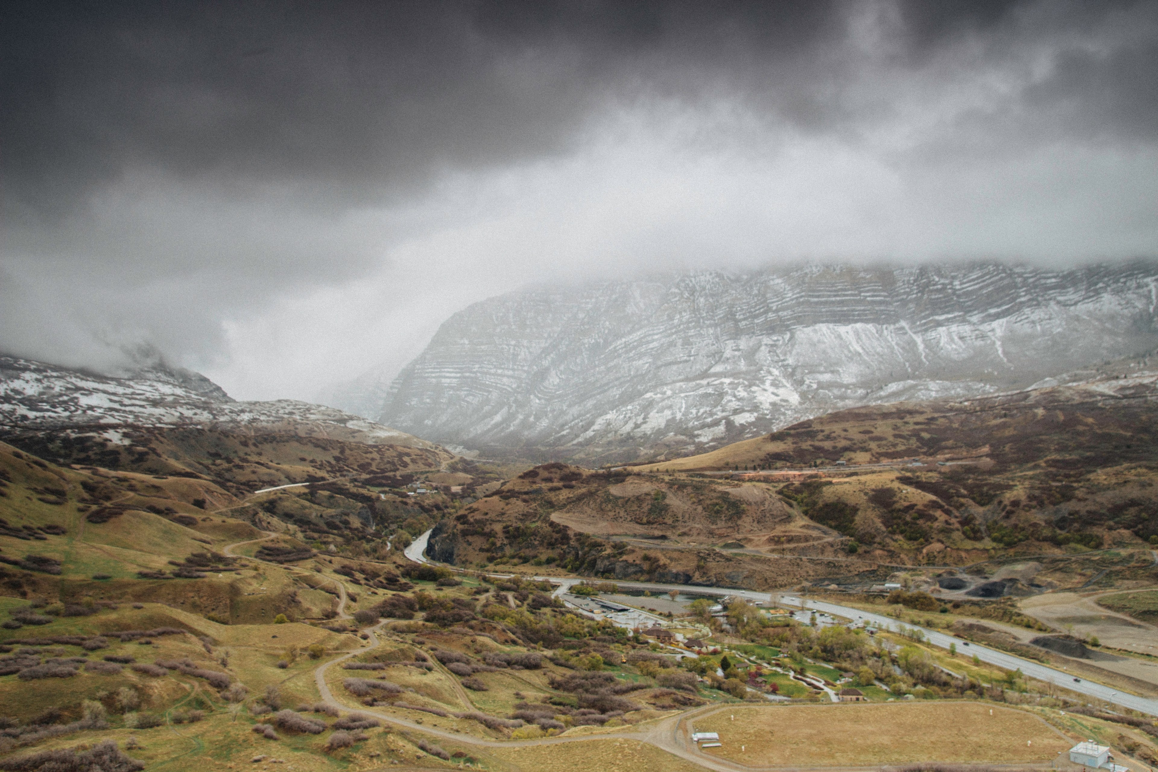 steep white mountains towering above a valley with sparse buildings, clouds over a mountain valley 4k, HD Wallpaper