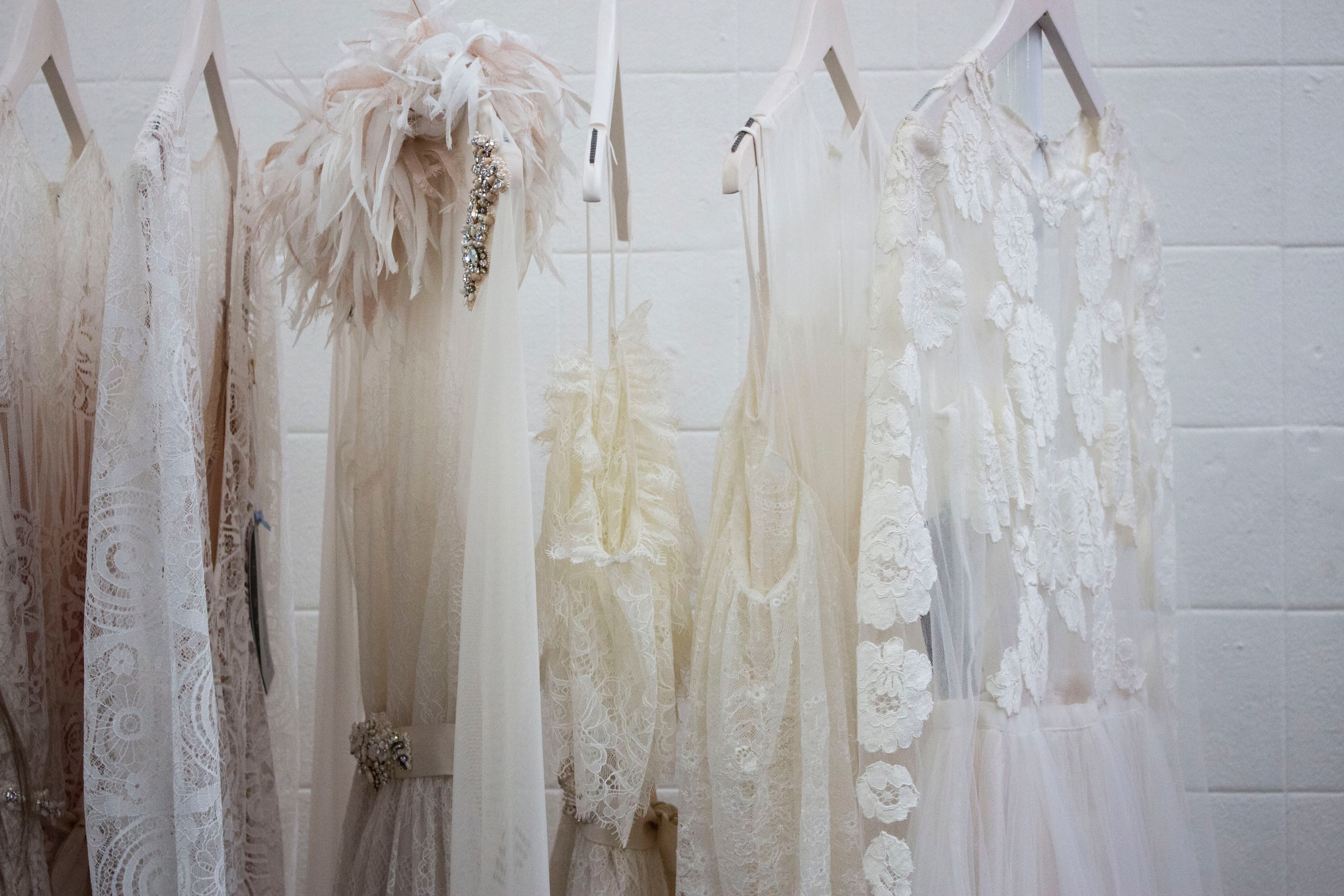 thin wedding dresses hang in front of a white brick wall at old truman brewery, wedding dress fashion 4k, HD Wallpaper