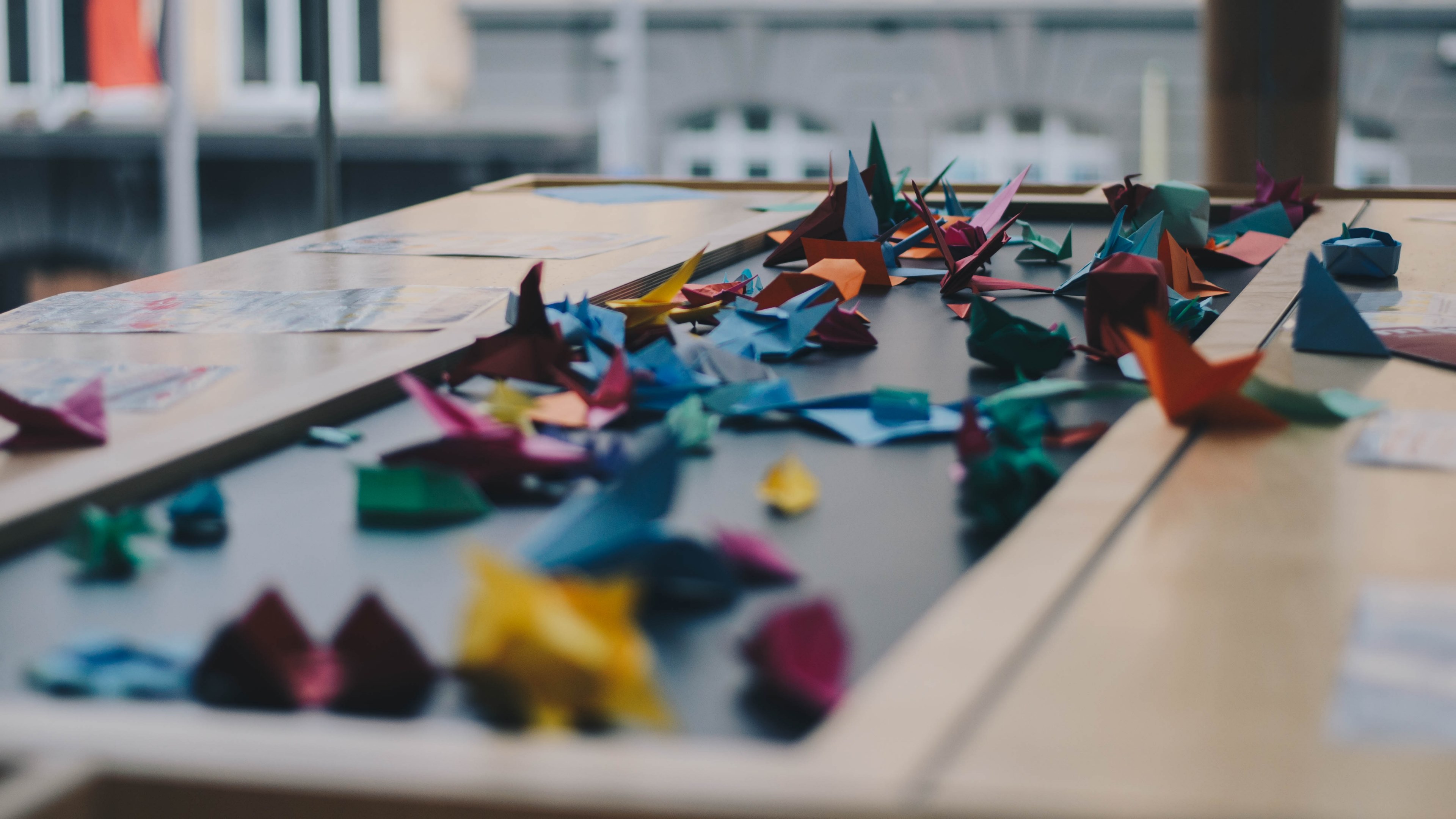a large number of colorful origami cranes scattered across a table, paper crane table 4k, HD Wallpaper