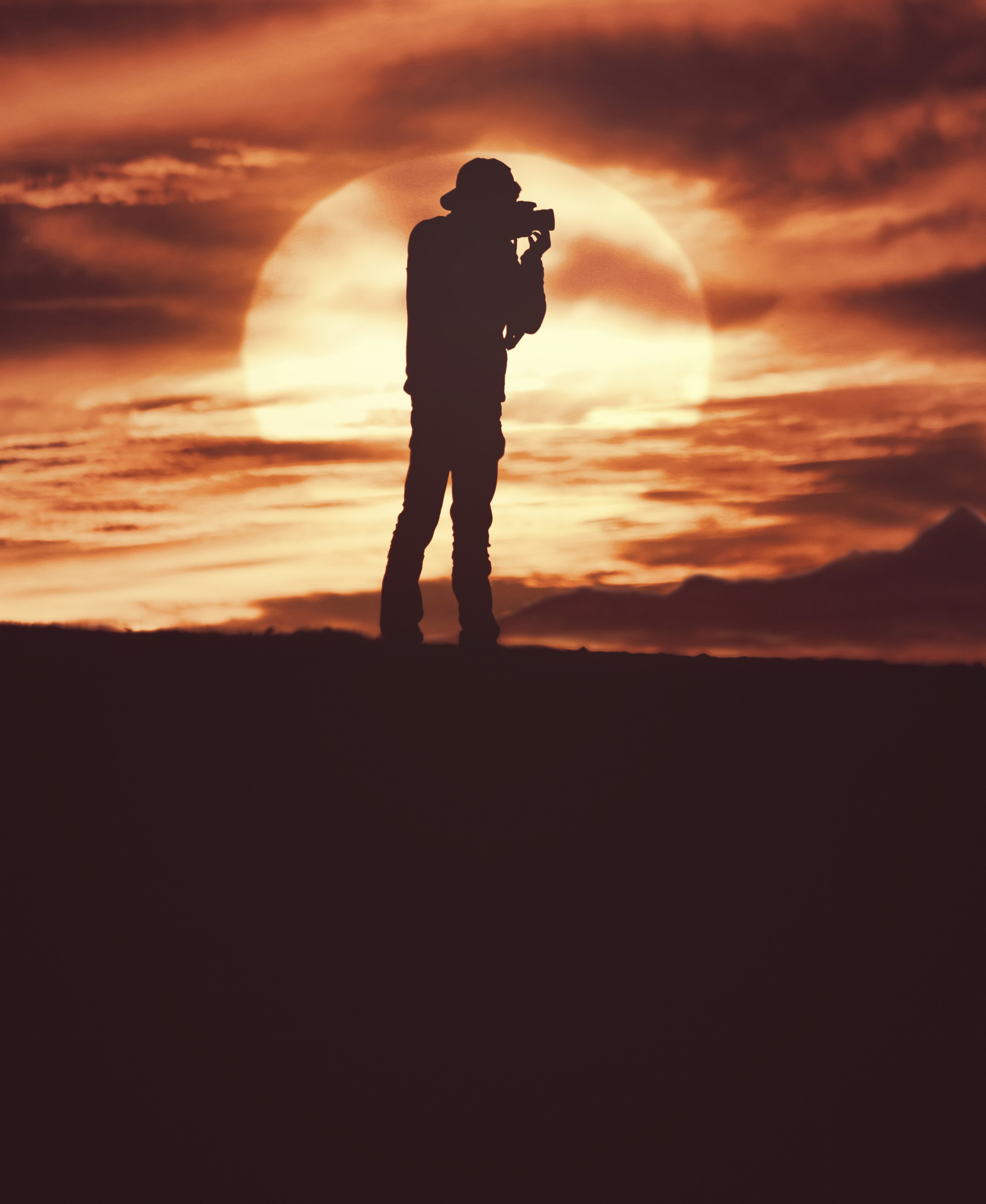 a silhouette of a man in a hat holding a camera in front of a cloudy orange sunset sky asilah morocco, wait the sunset 4k, Phone HD Wallpaper
