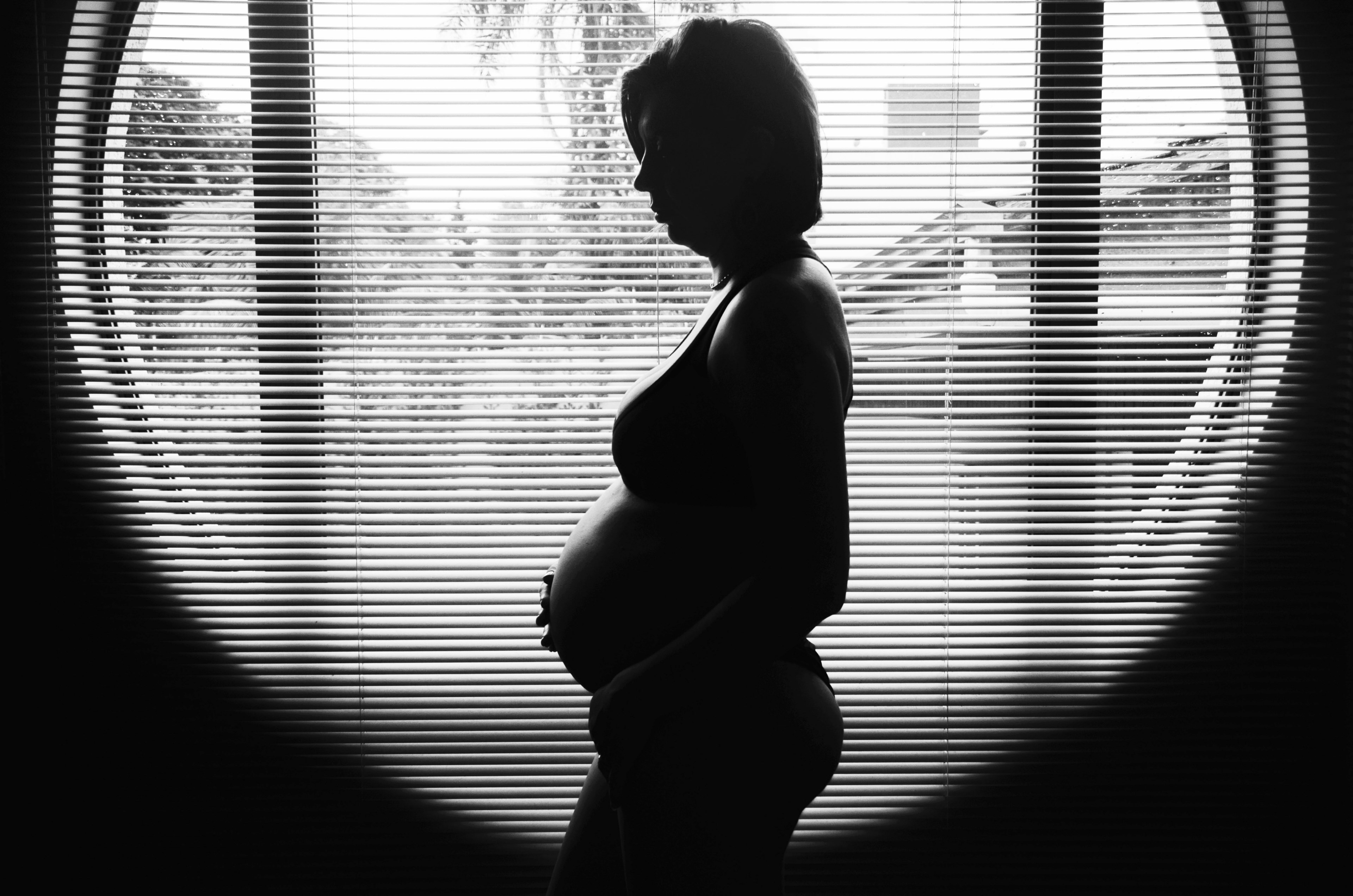 the black and white silhouette of a pregnant woman standing in front of a round window, _silhouetted baby bump 4k, HD Wallpaper