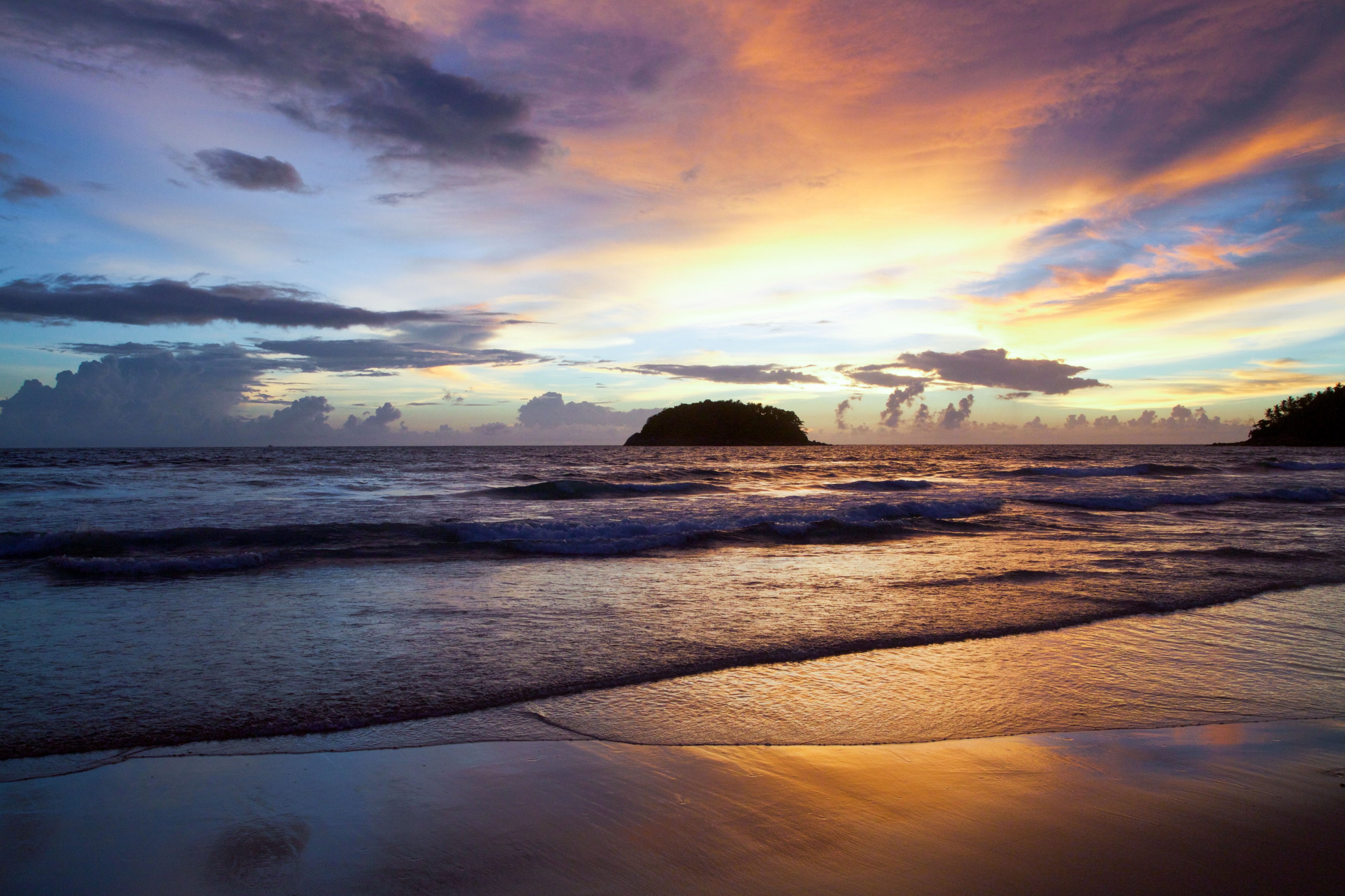 look out to sea from a smooth sandy shore towards a silhouette island_ the tide breaks gently and the sky is blue and yellow with some thin cloud at sunrise or sunset, sunset beach sunrise 4k, HD Wallpaper