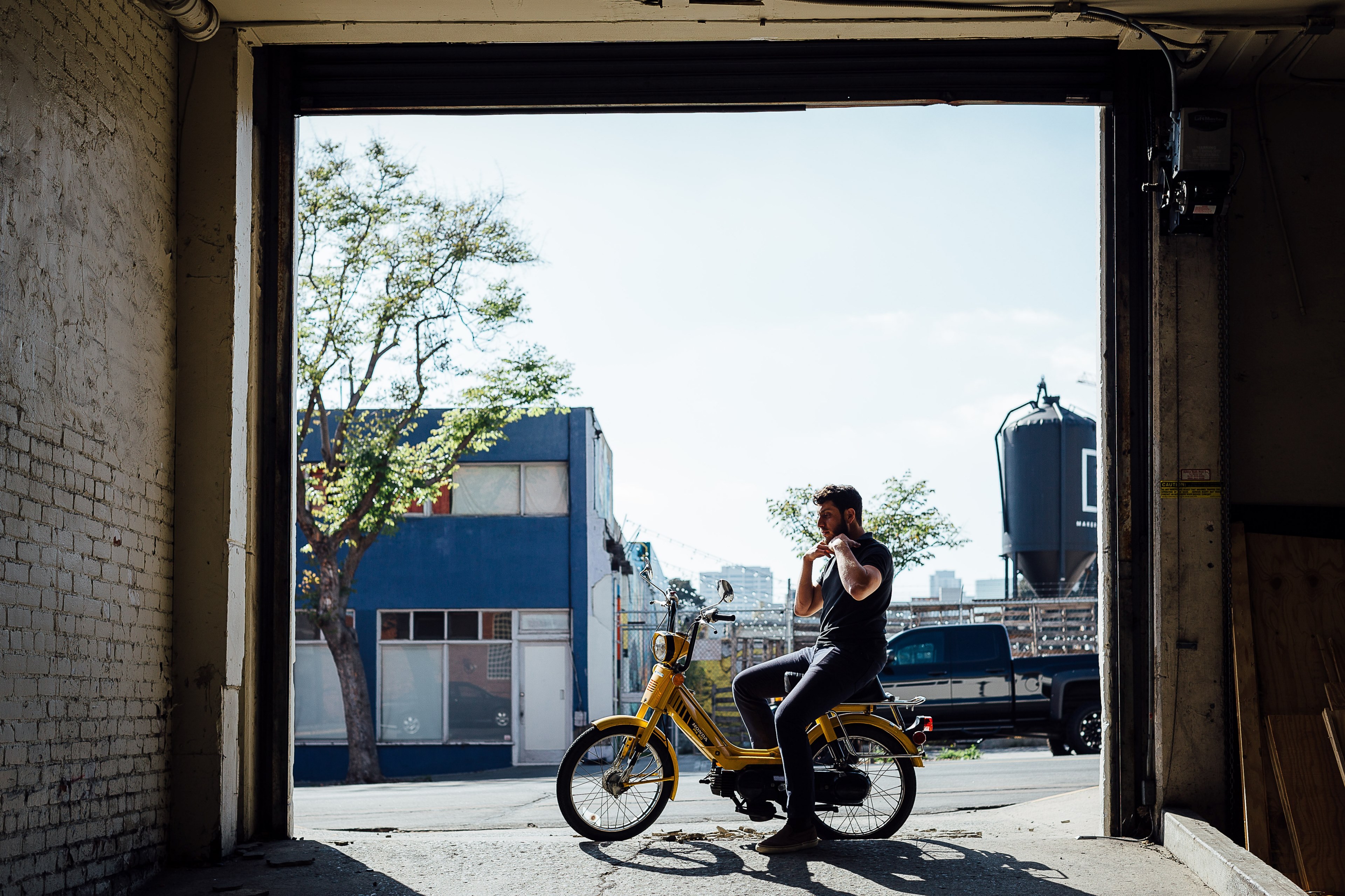 a man on a yellow moped in front of a white brick garage at moniker warehouse, moniker warehouse moped 4k, HD Wallpaper