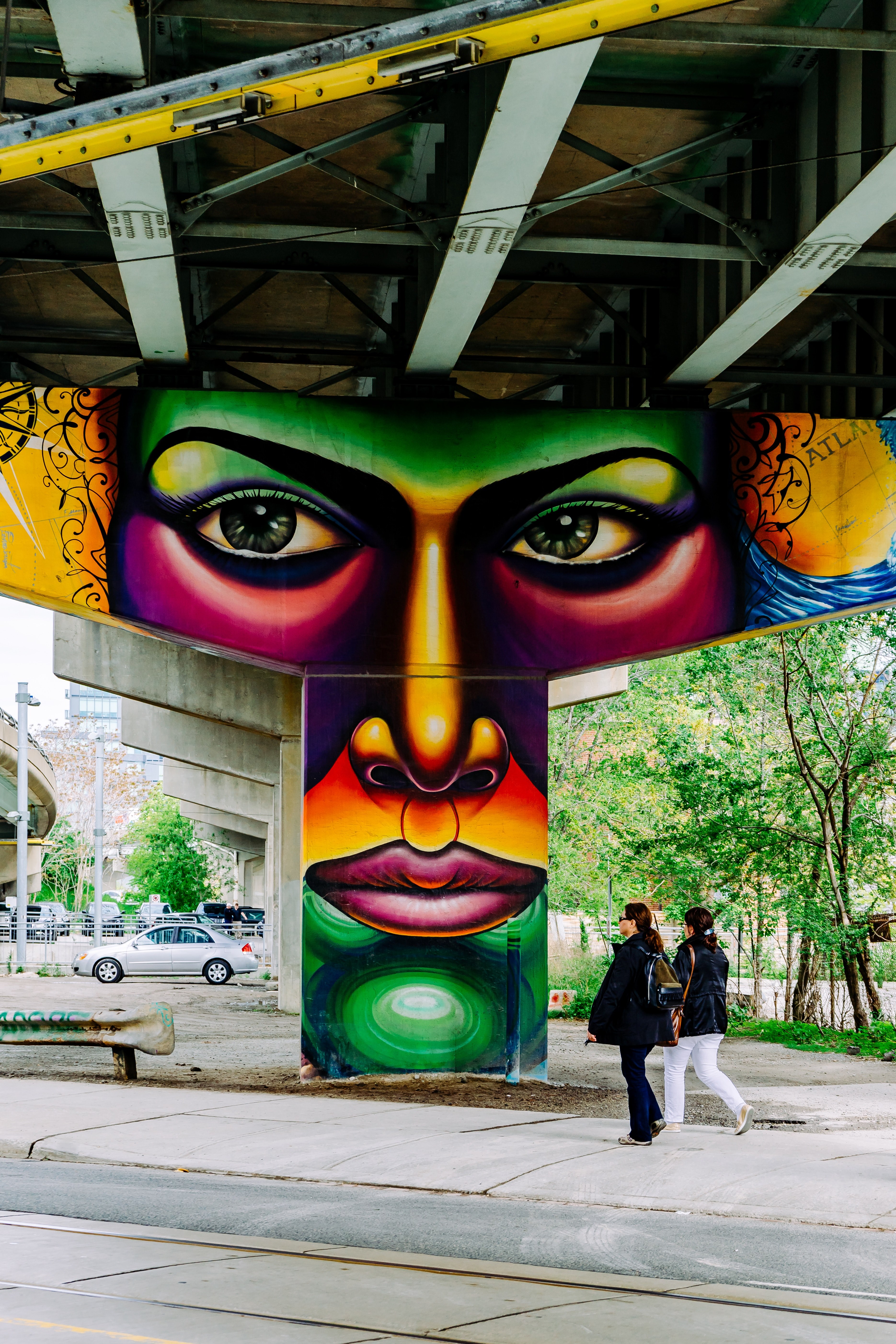 colorful graffiti of face on bridge structure with people walking on underpass 507 king st e, shes watching 4k, Phone HD Wallpaper