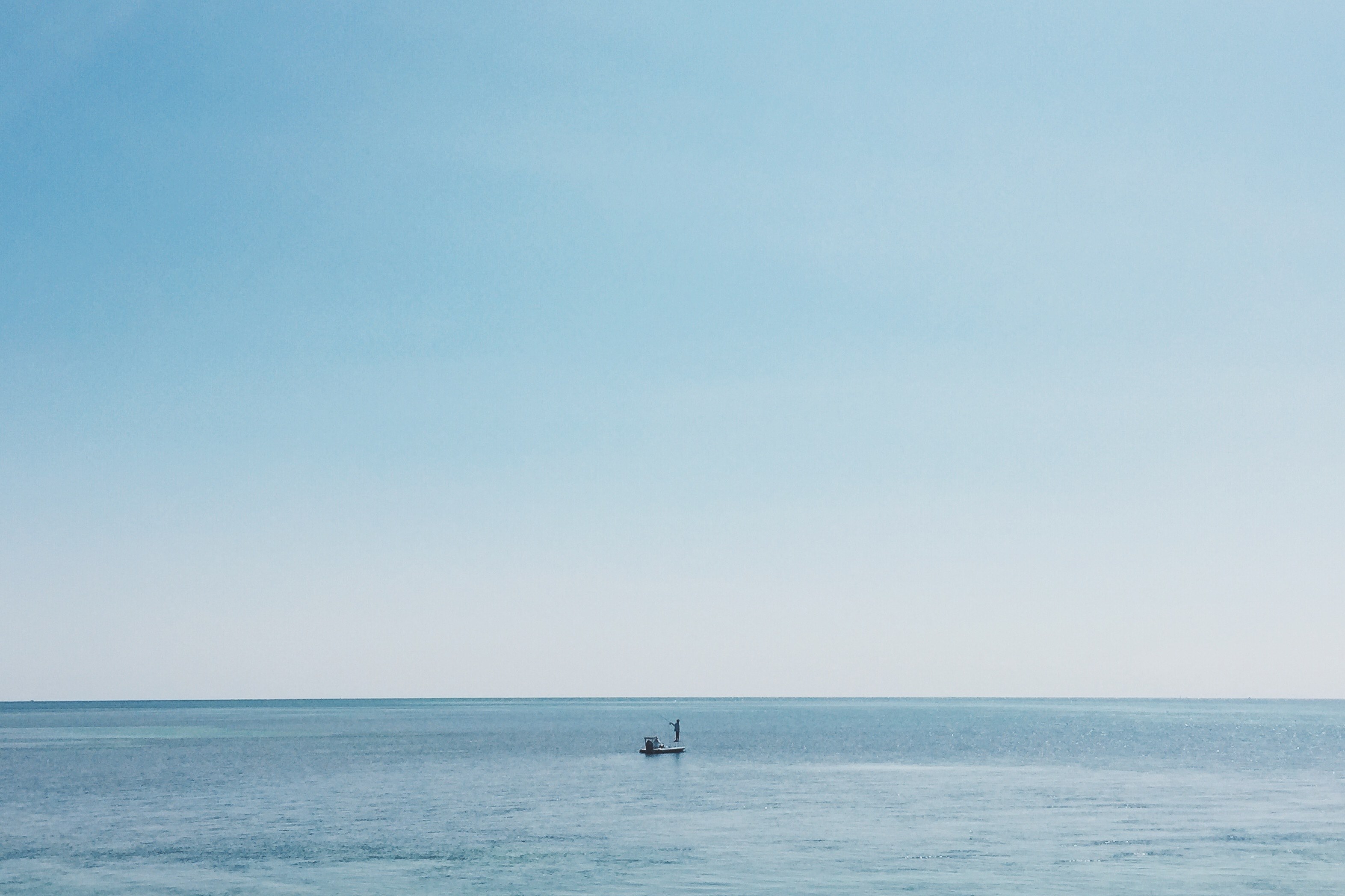 a fisherman on his boat on the calm ocean where the water meets the horizon, distant fisherman in the sea 4k, HD Wallpaper
