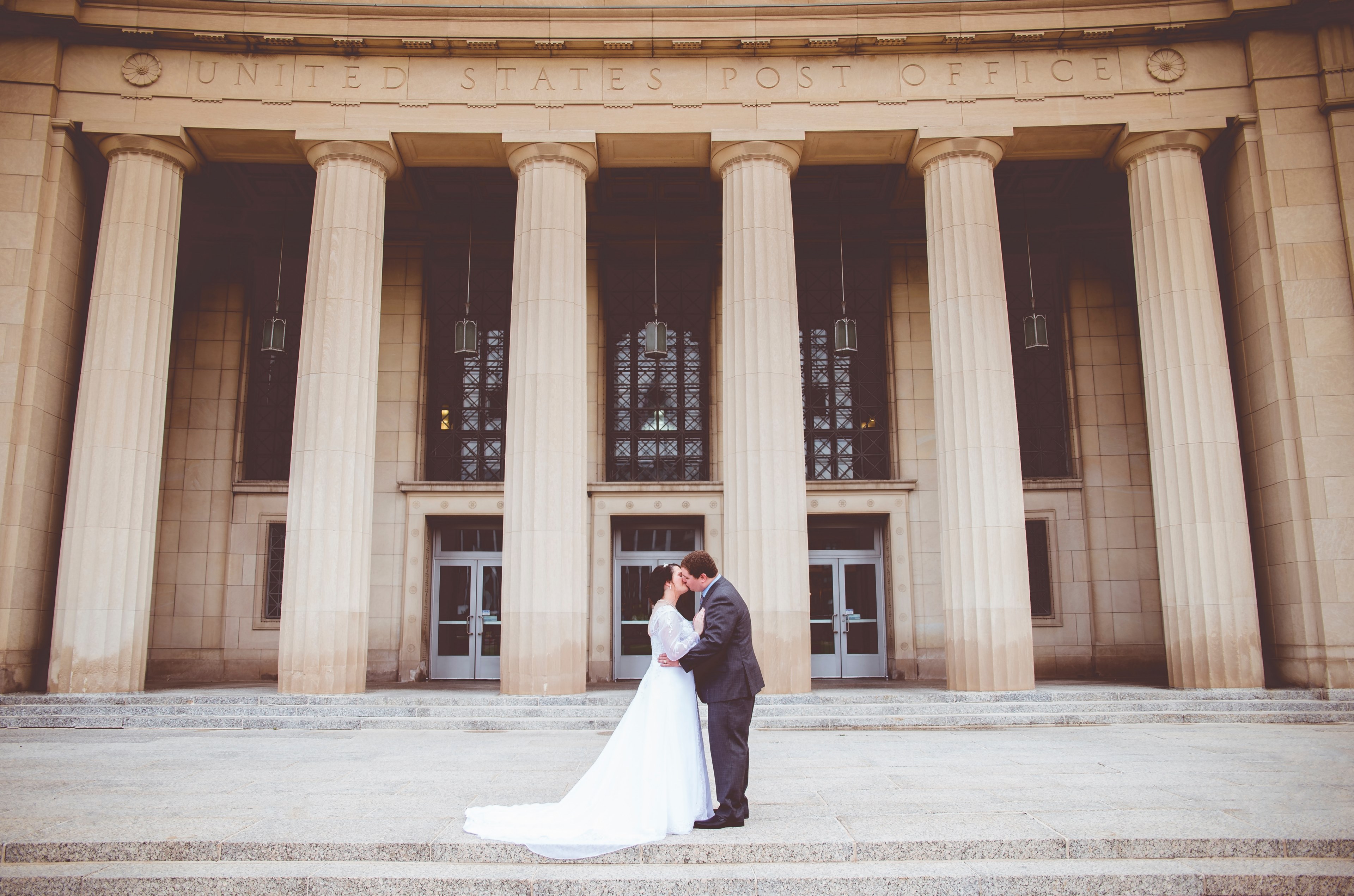 a married couple kisses in front of a us post office building with tall columns, post office wedding 4k, HD Wallpaper
