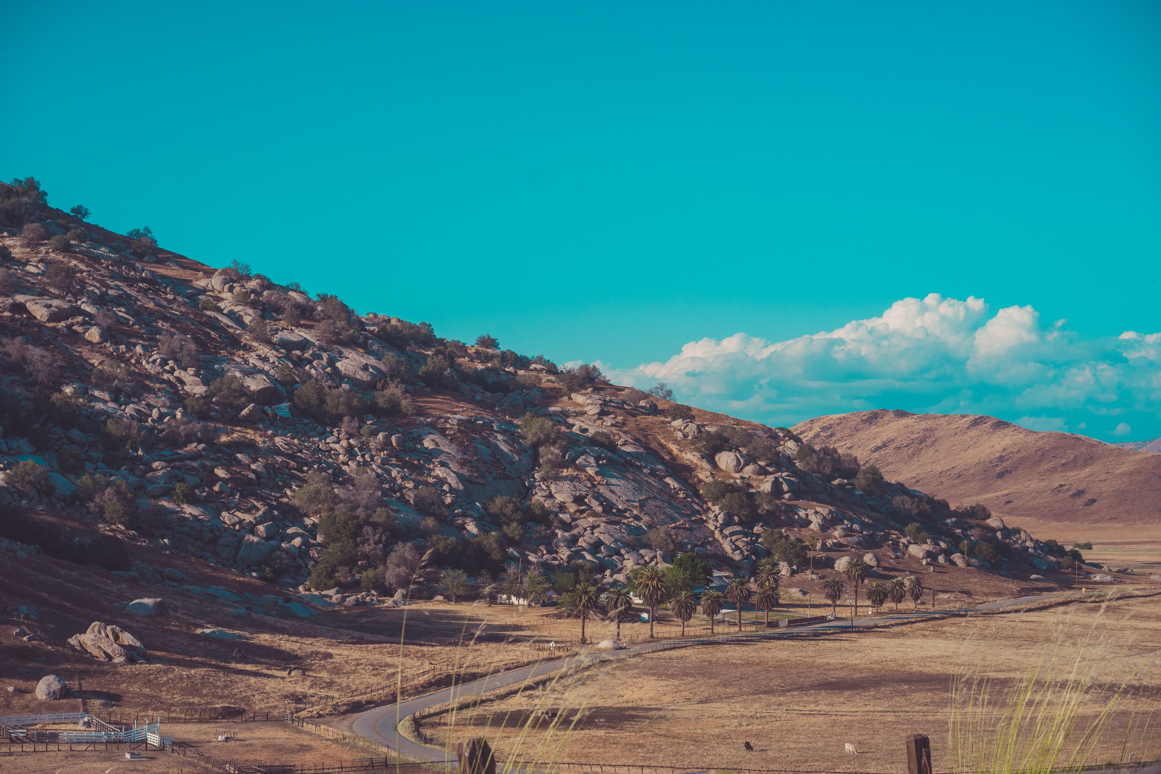 a semi arid landscape with a narrow winding road winding around a rocky slope, flat rocks on the arid hills 4k, HD Wallpaper