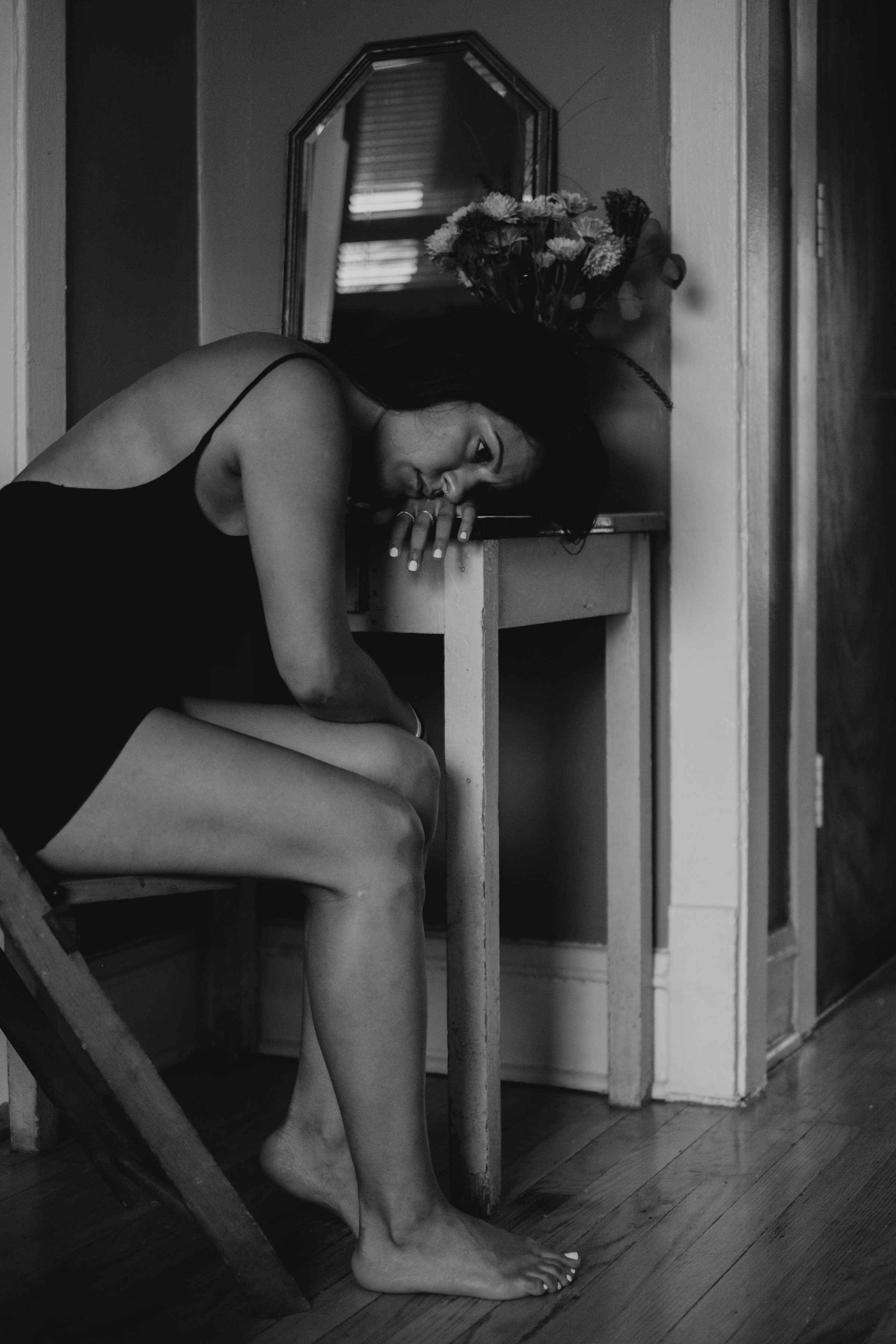 a sad woman in black and white with bare legs lays her head down on a table, lost in thought 4k, Phone HD Wallpaper