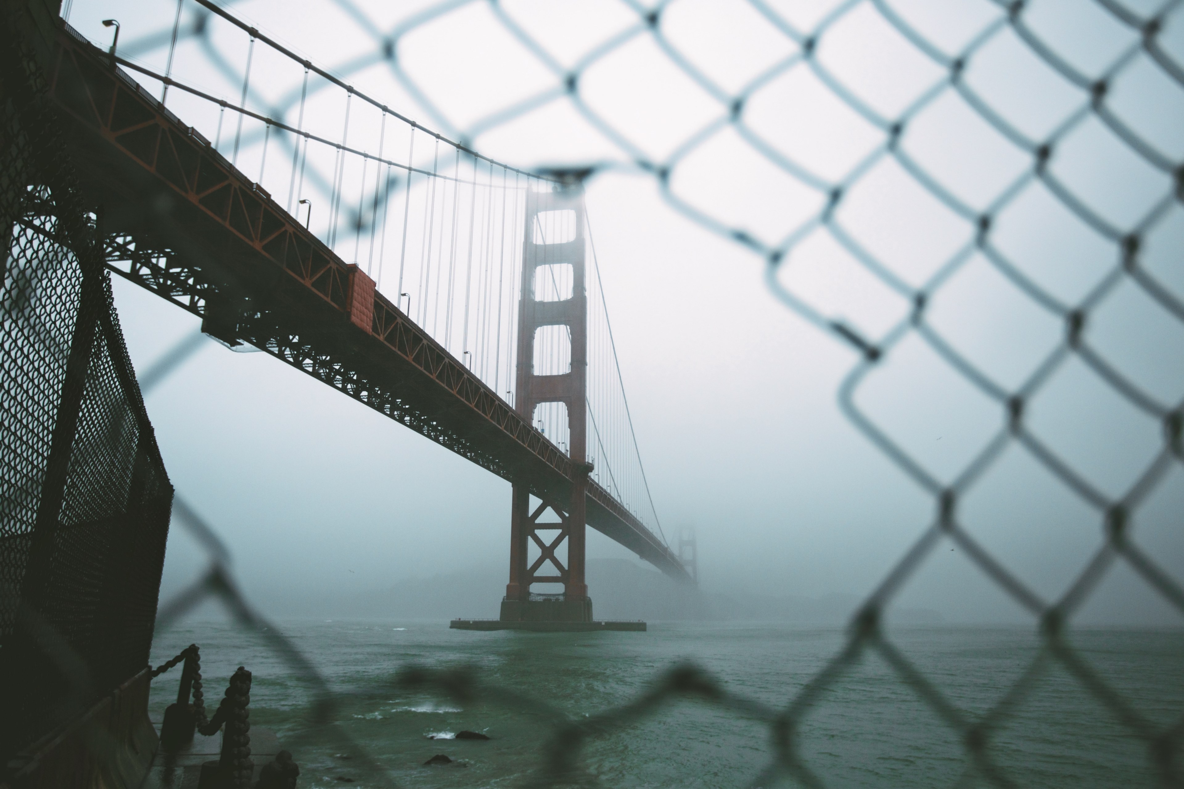 aerial view from a chainlink fence of the san francisco golden gate bridge covered by fog, san franciscos bridge 4k, HD Wallpaper
