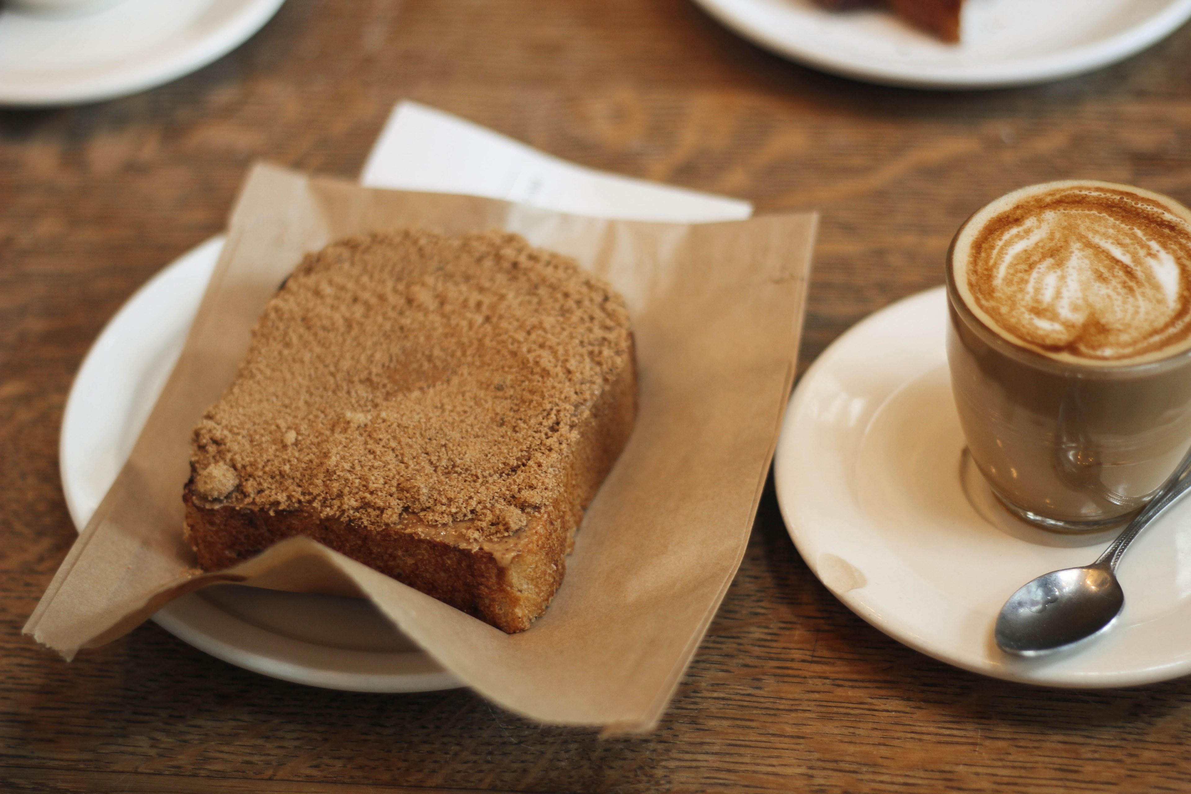 latte with foam on a white saucer with a spoon and a piece of toast with a sweet crumb topping next to it, coffee and coffee cake 4k, HD Wallpaper