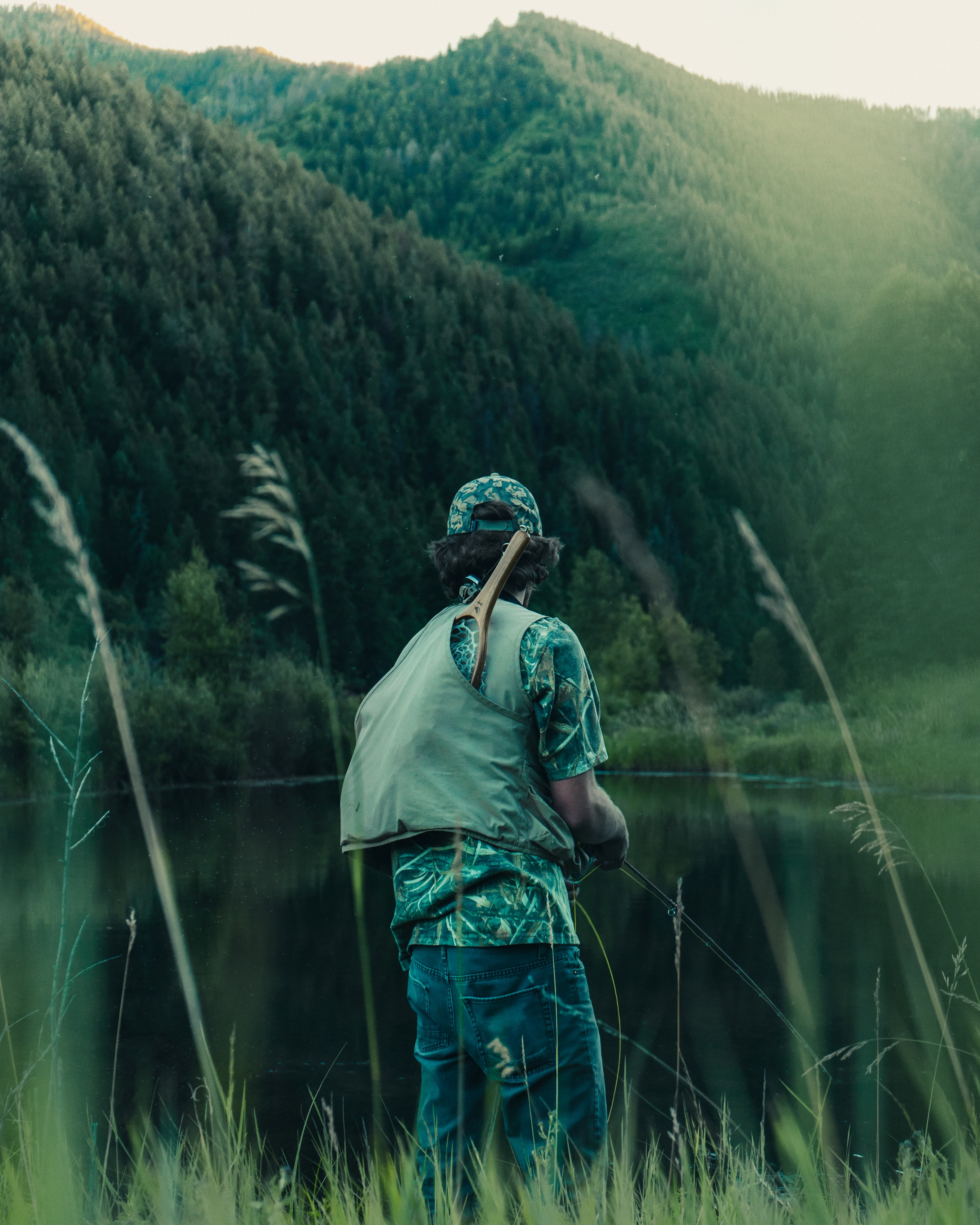 a man with a fishing net on his back over a mountain lake, fisherman near a lake 4k, Phone HD Wallpaper