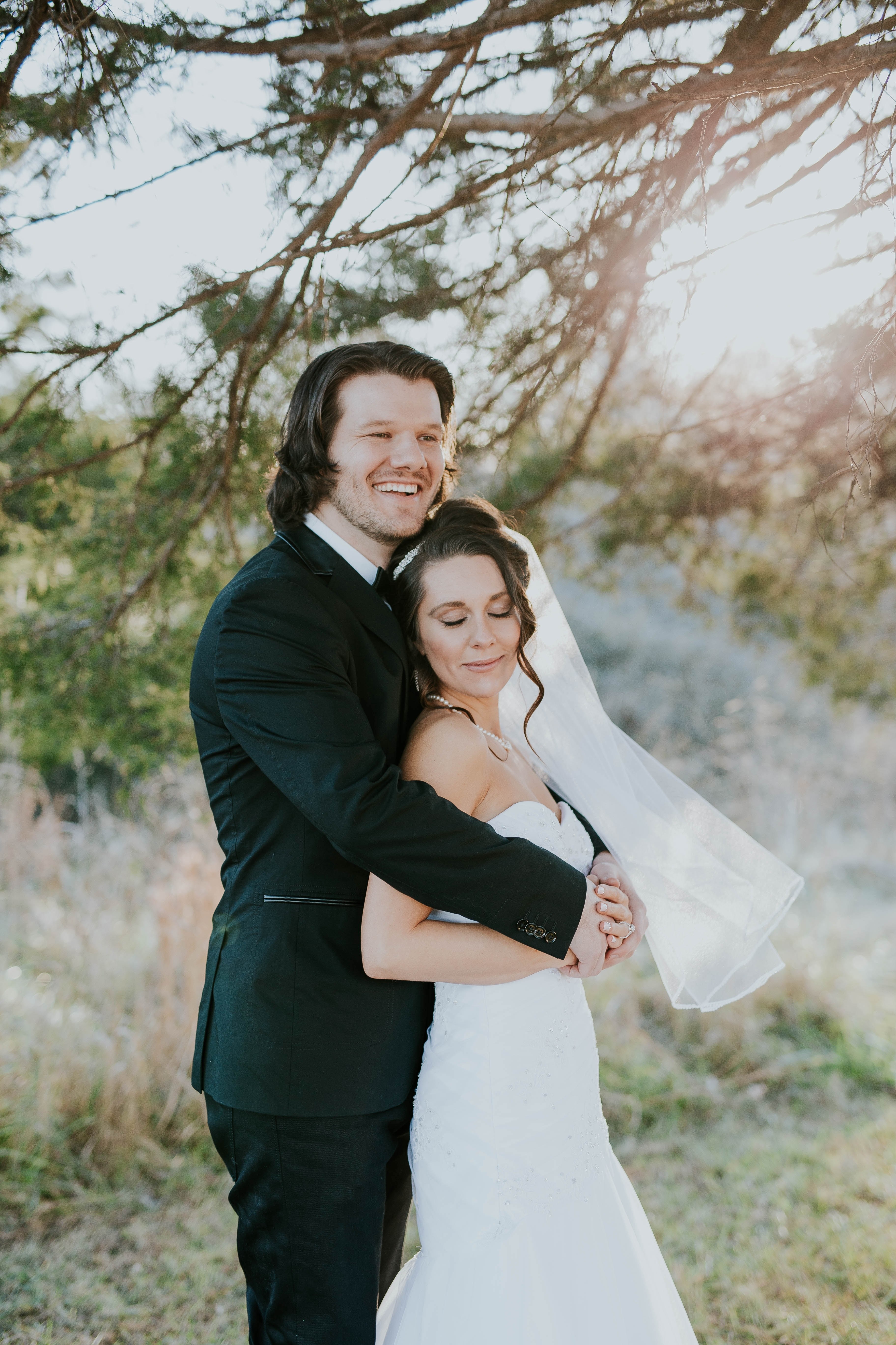 a bride in her wedding dress and groom in a suit embrace in a sunny meadow, _bride leans into husband 4k, Phone HD Wallpaper