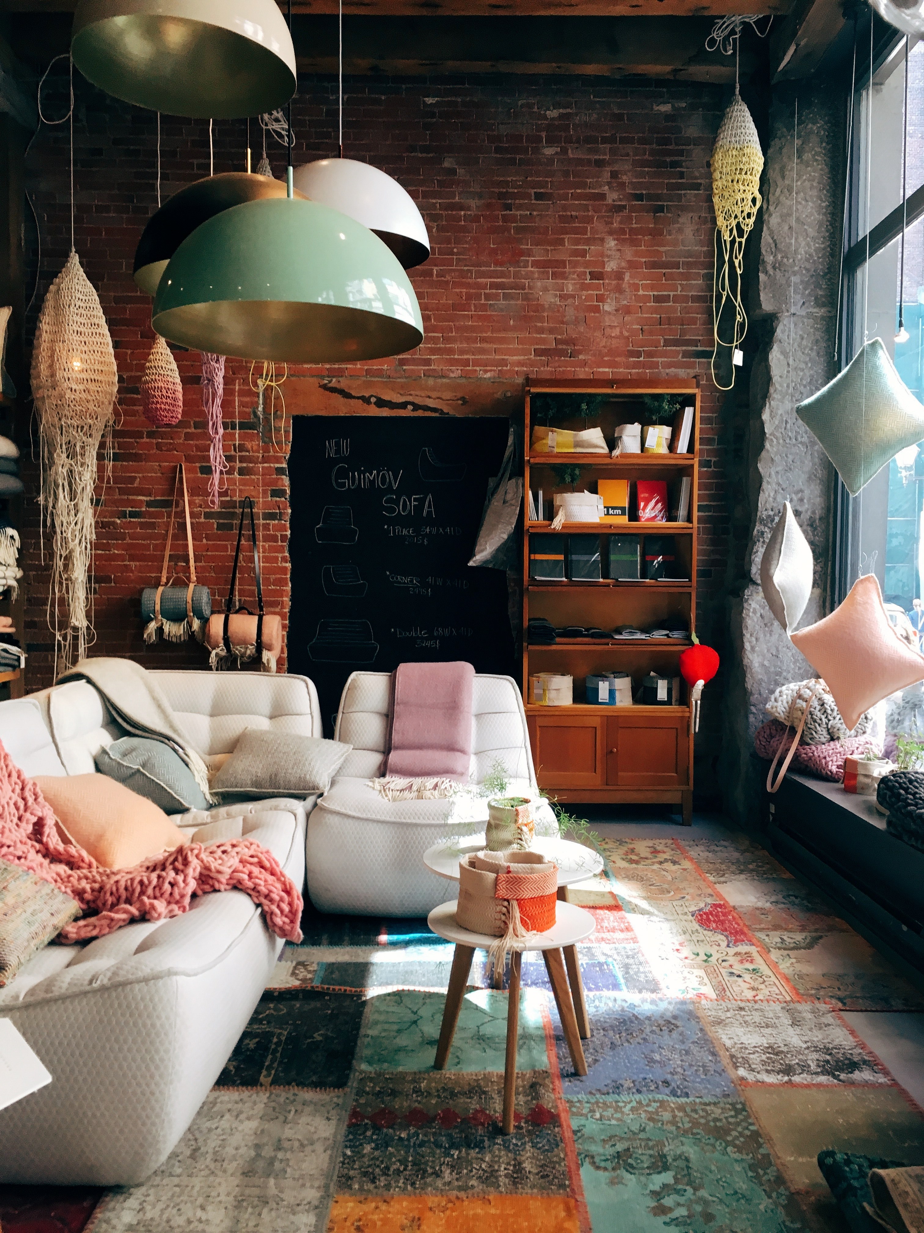a living room having a brick wall glass windows and containing a white sofa with throw pillows in canada, furnished living room_ 4k, Phone HD Wallpaper