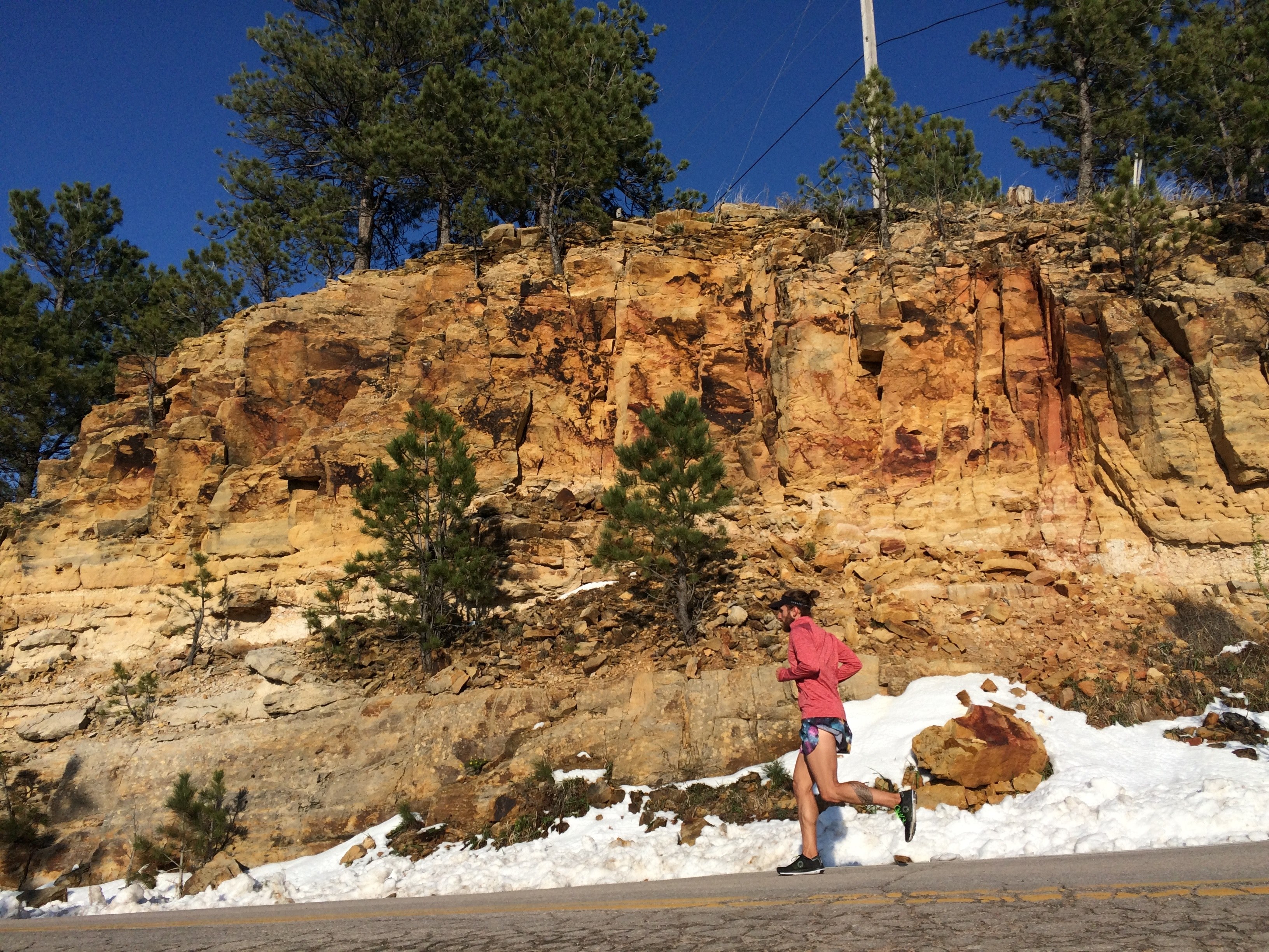a girl running at the bottom of a rock hill on a warm winter day, running by a winter mountain 4k, HD Wallpaper