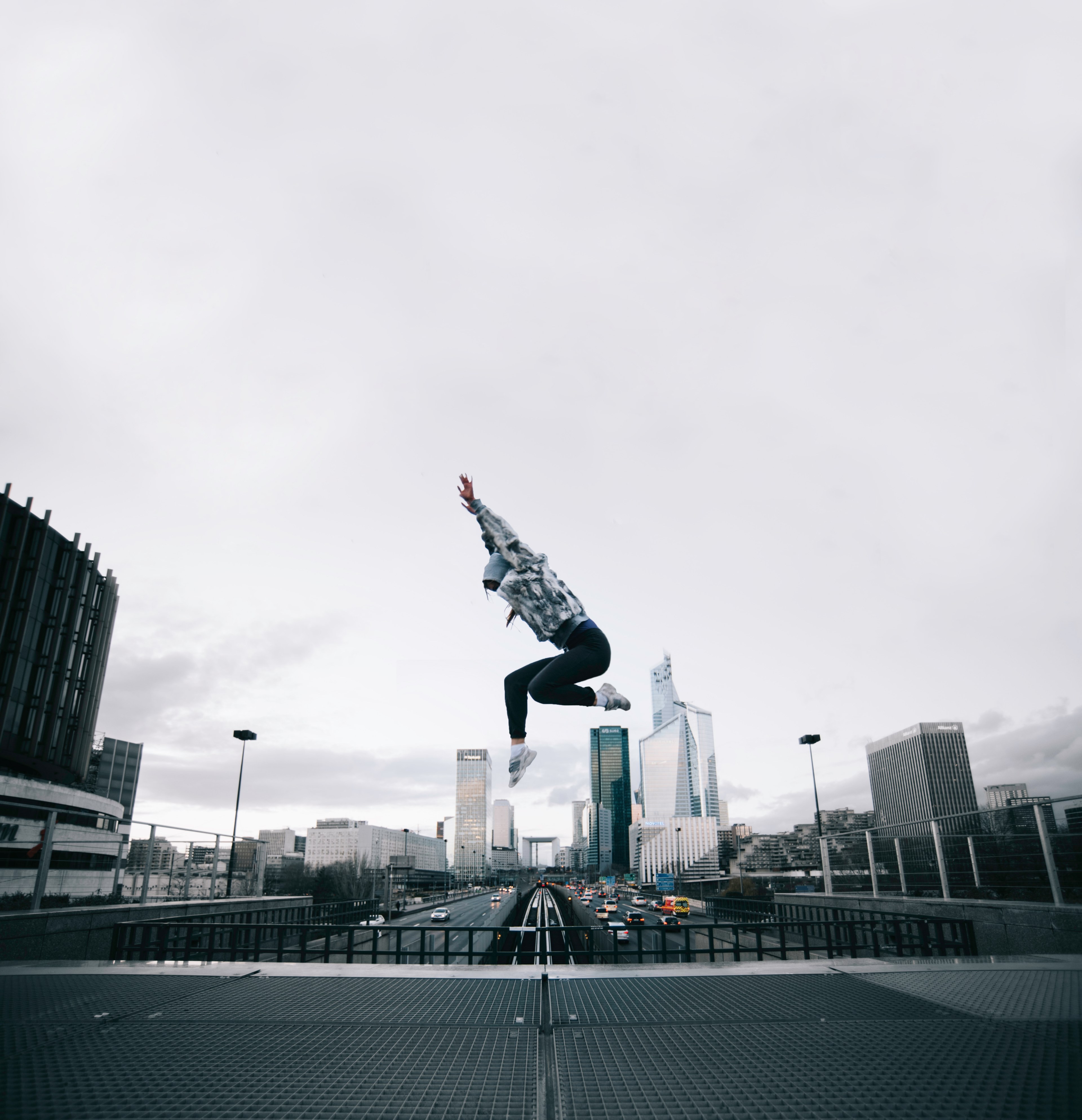 a woman jumping in front of an urban backdrop of buildings and roads, end of the line_ 4k, Phone HD Wallpaper