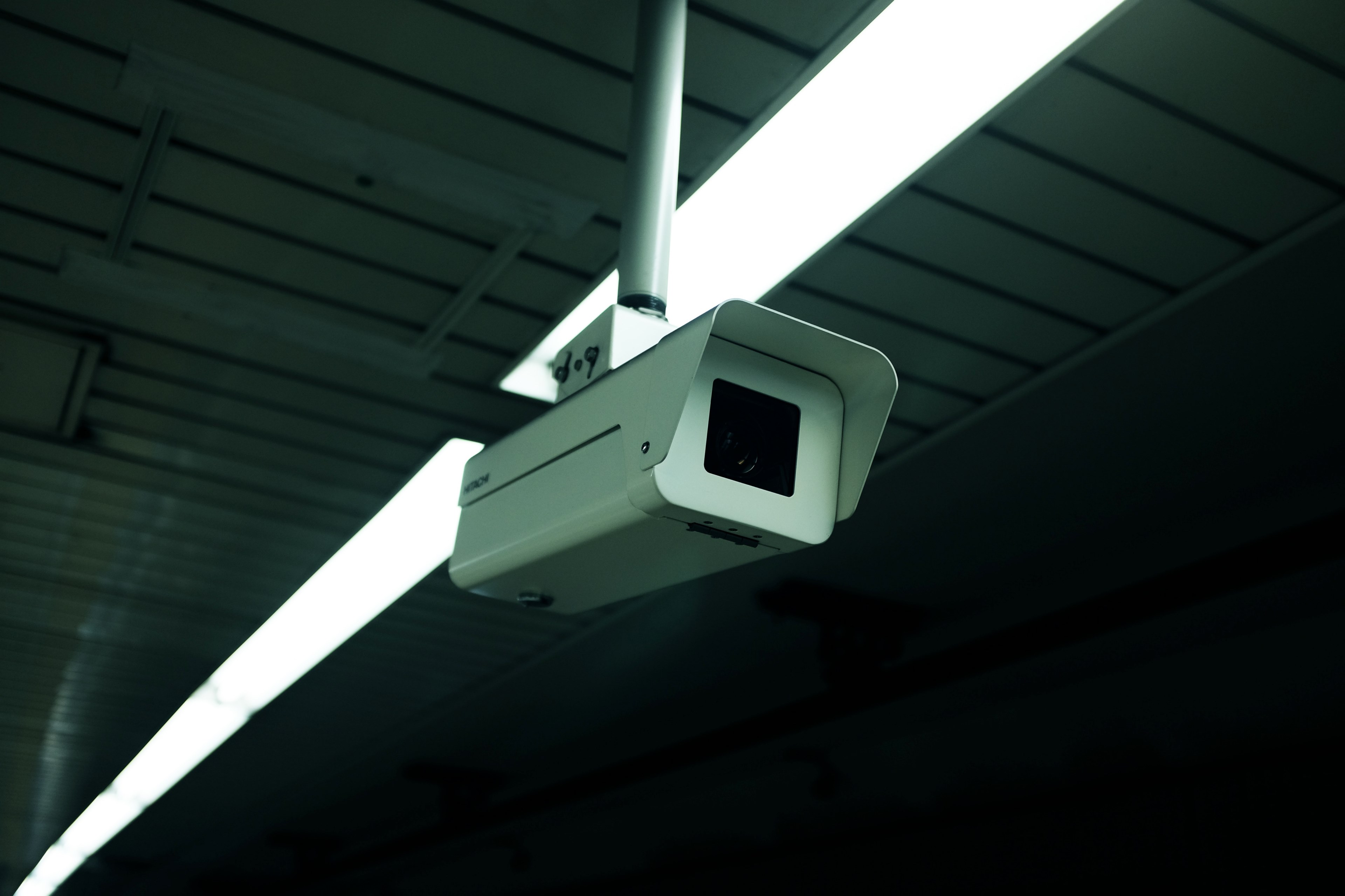 white surveillance camera monitoring a dark space with lined ceilings and overhead lights, ceiling surveillance camera 4k, HD Wallpaper