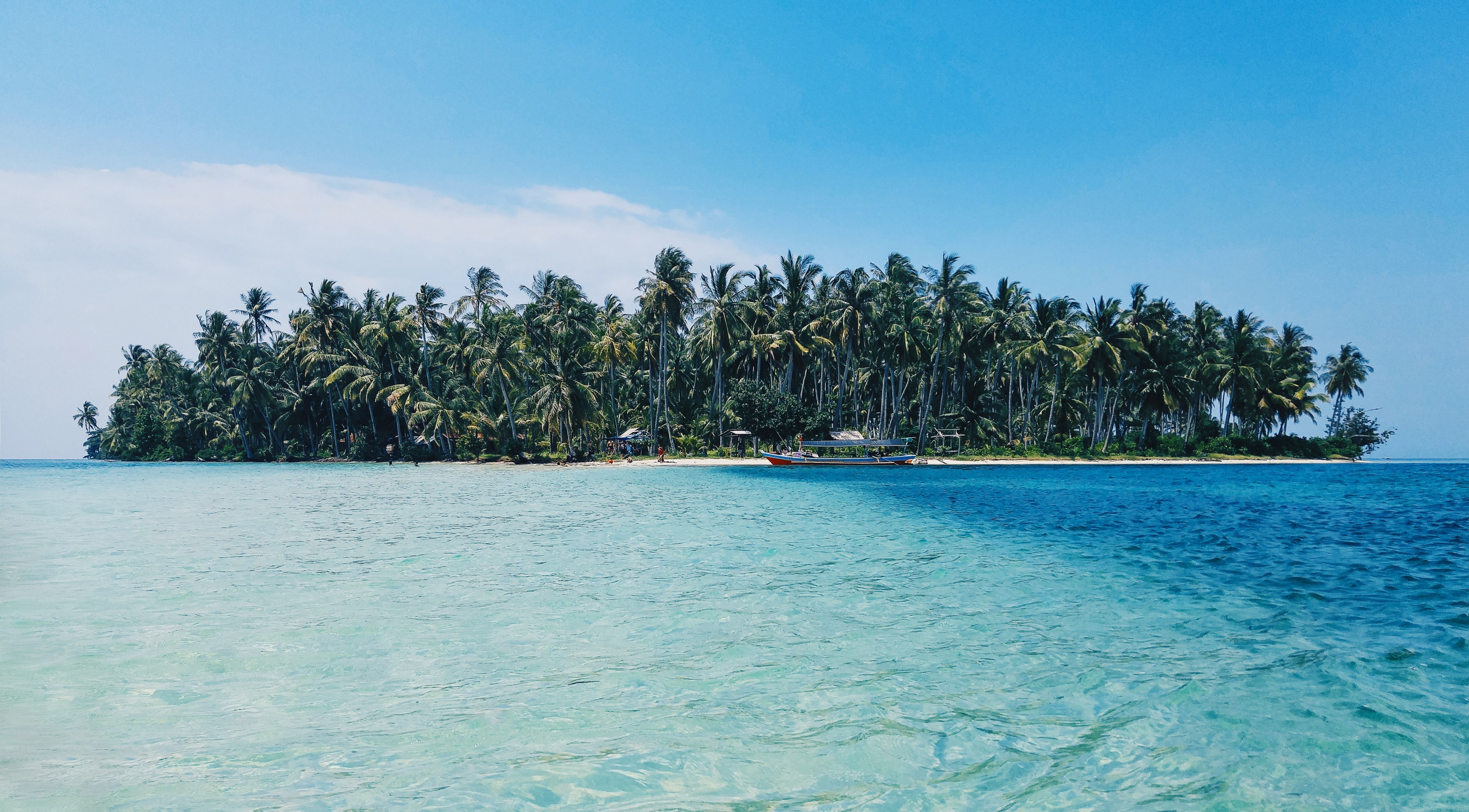 distant view of a boat moored at an island covered with tropical trees, serene tropical island 4k, HD Wallpaper