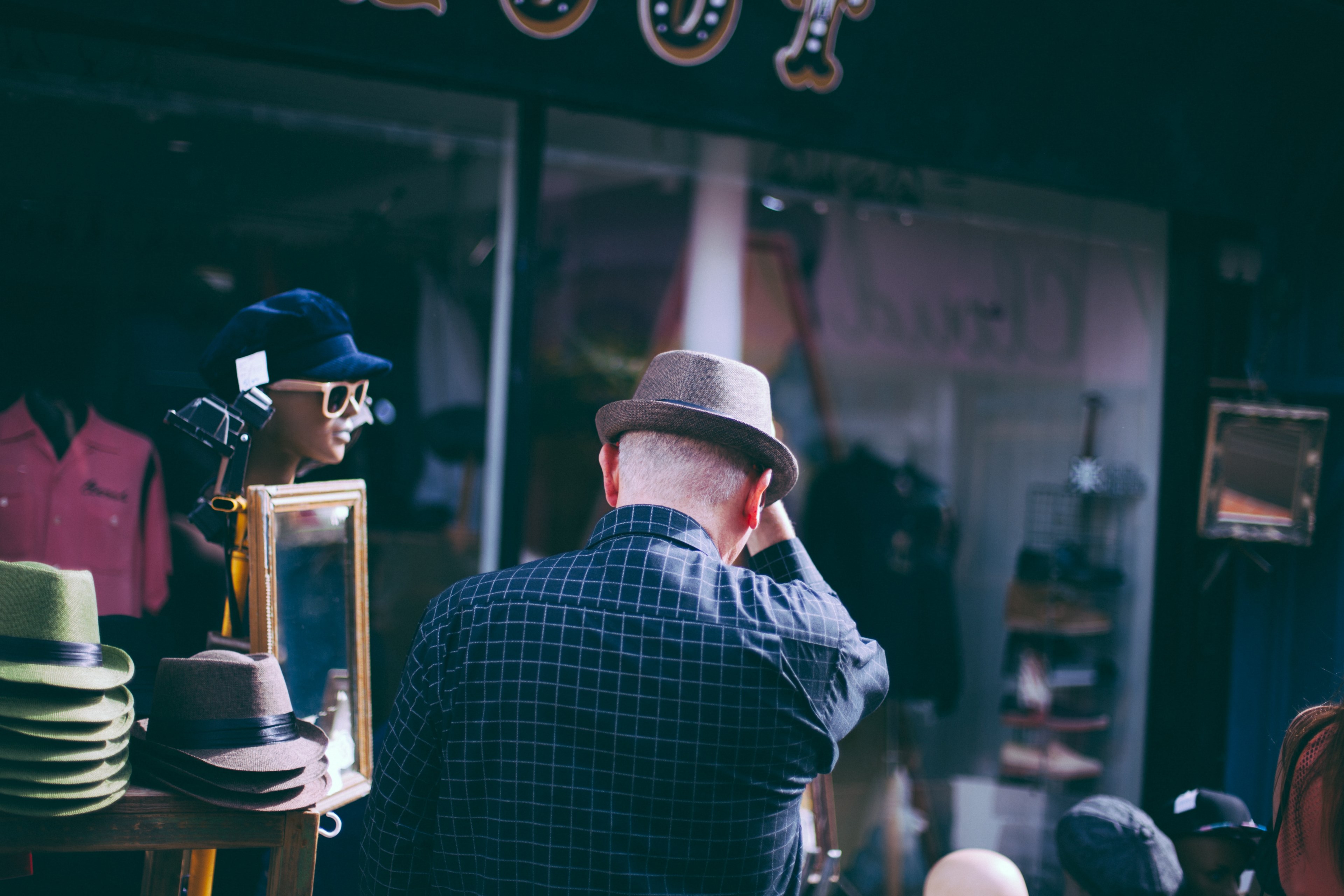 a man facing away tries on a hat next to a store display in brighton, man trying on a hat 4k, HD Wallpaper