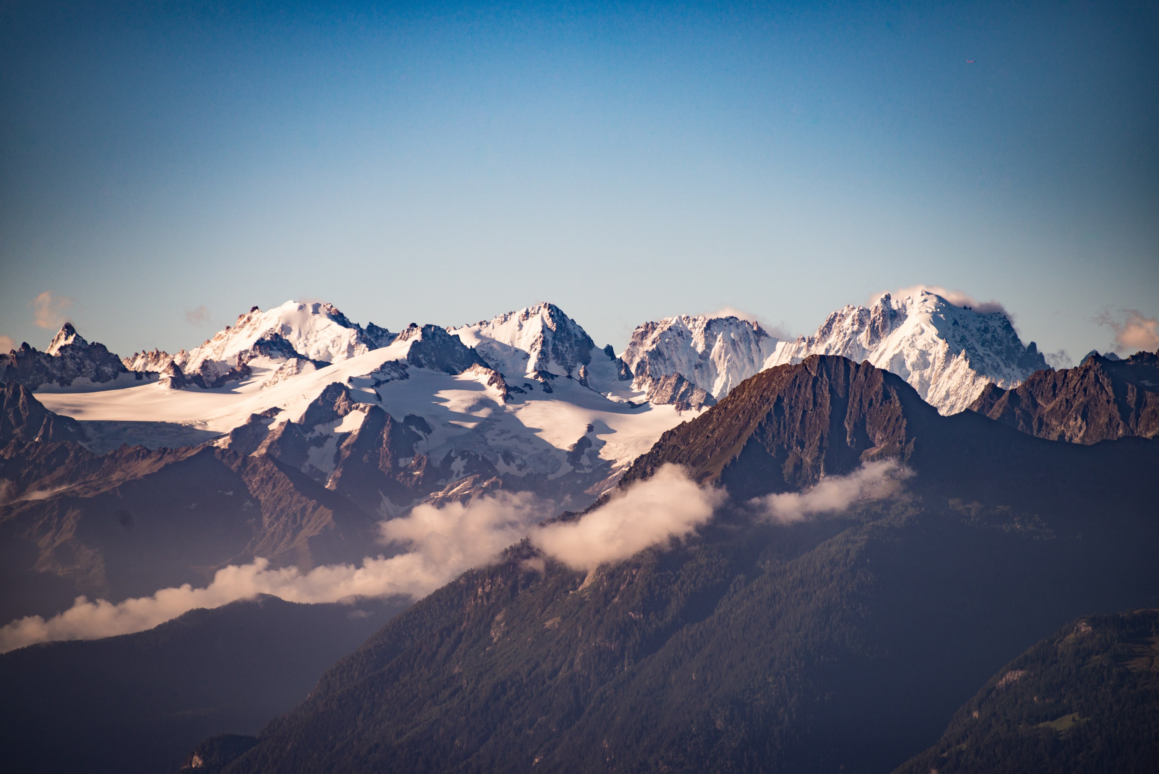 a mountain range partly covered in snow with low hanging clouds in between, summits in the sky 4k, HD Wallpaper